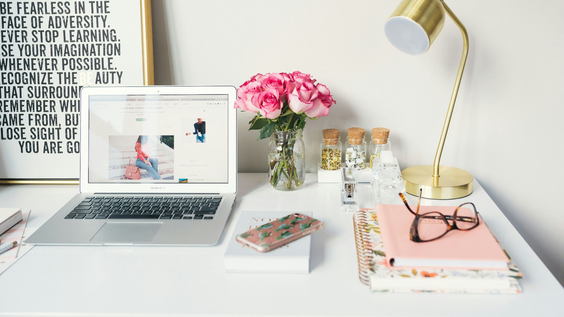 MacBook Air beside gold-colored study lamp and spiral books