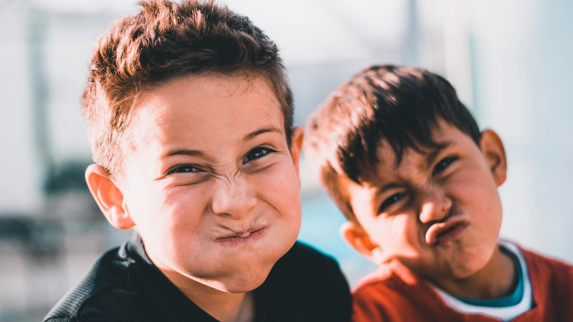 shallow focus photography of two boys doing wacky faces
