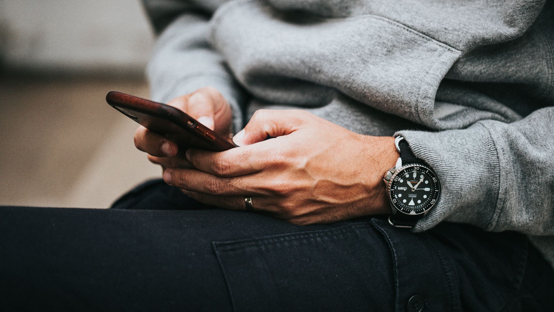 person in gray sweater wearing black and silver chronograph watch