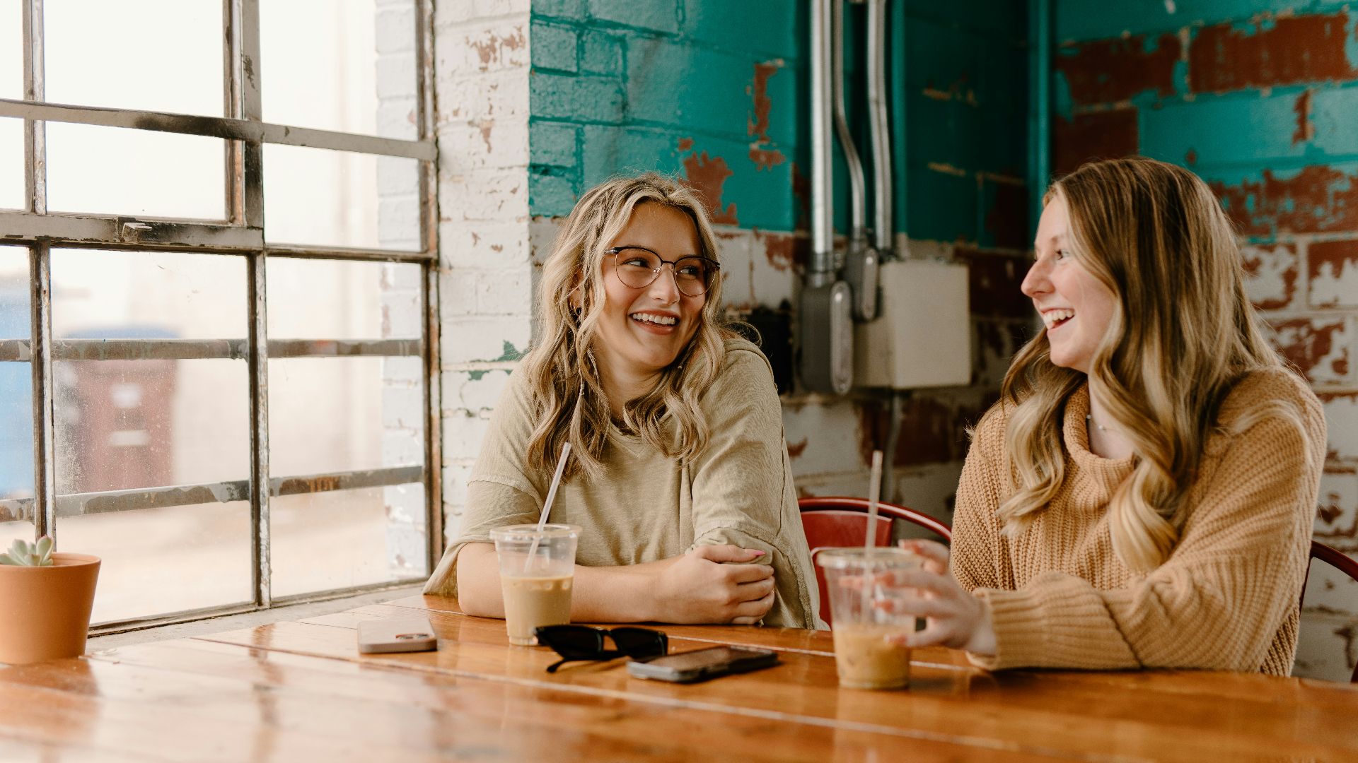 a couple of women sitting at a wooden table
