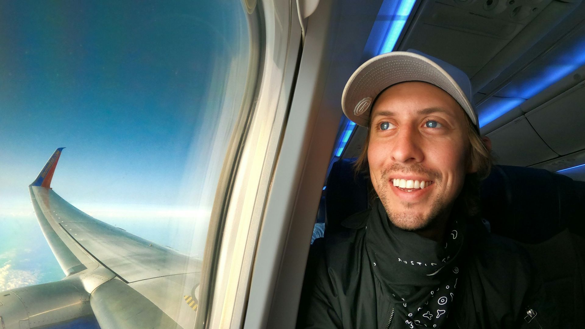 smiling woman in black jacket wearing blue cap