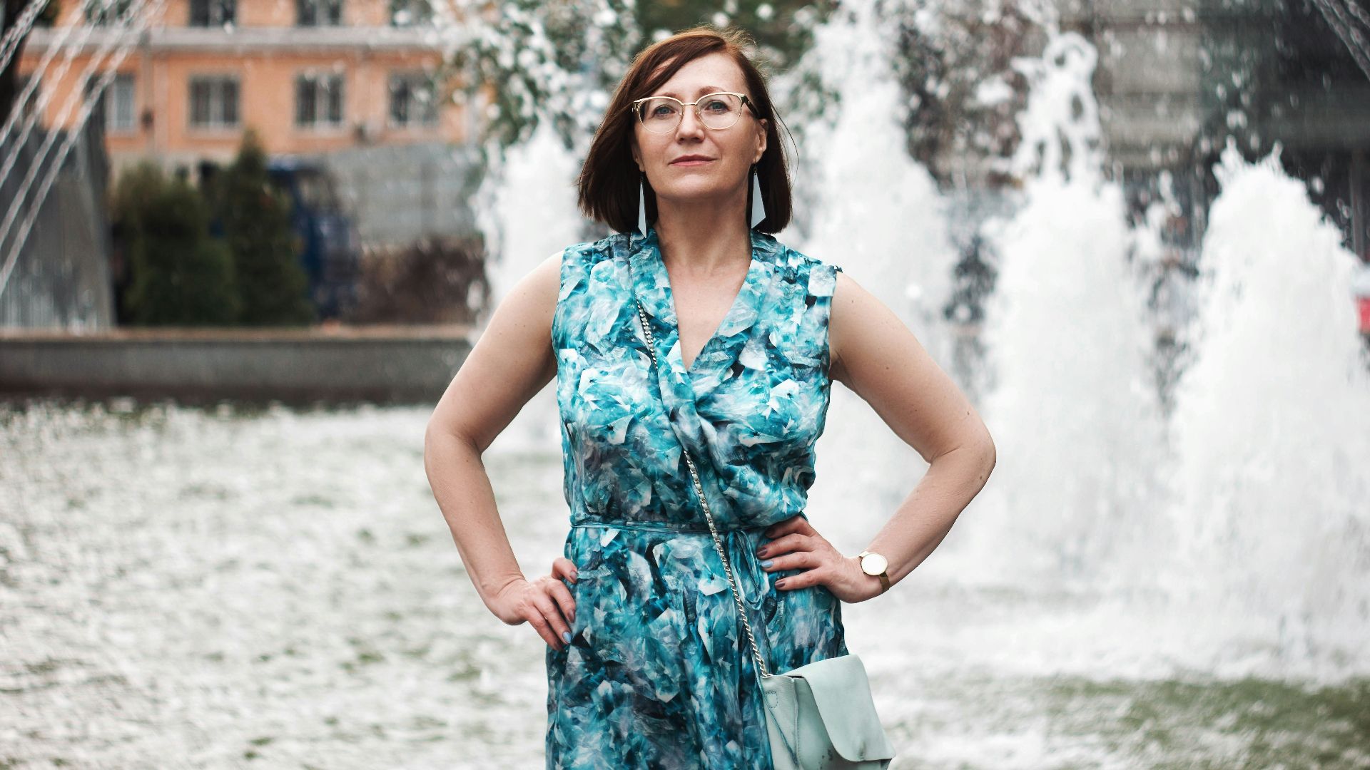 woman in blue and white floral sleeveless dress standing on snow covered ground during daytime