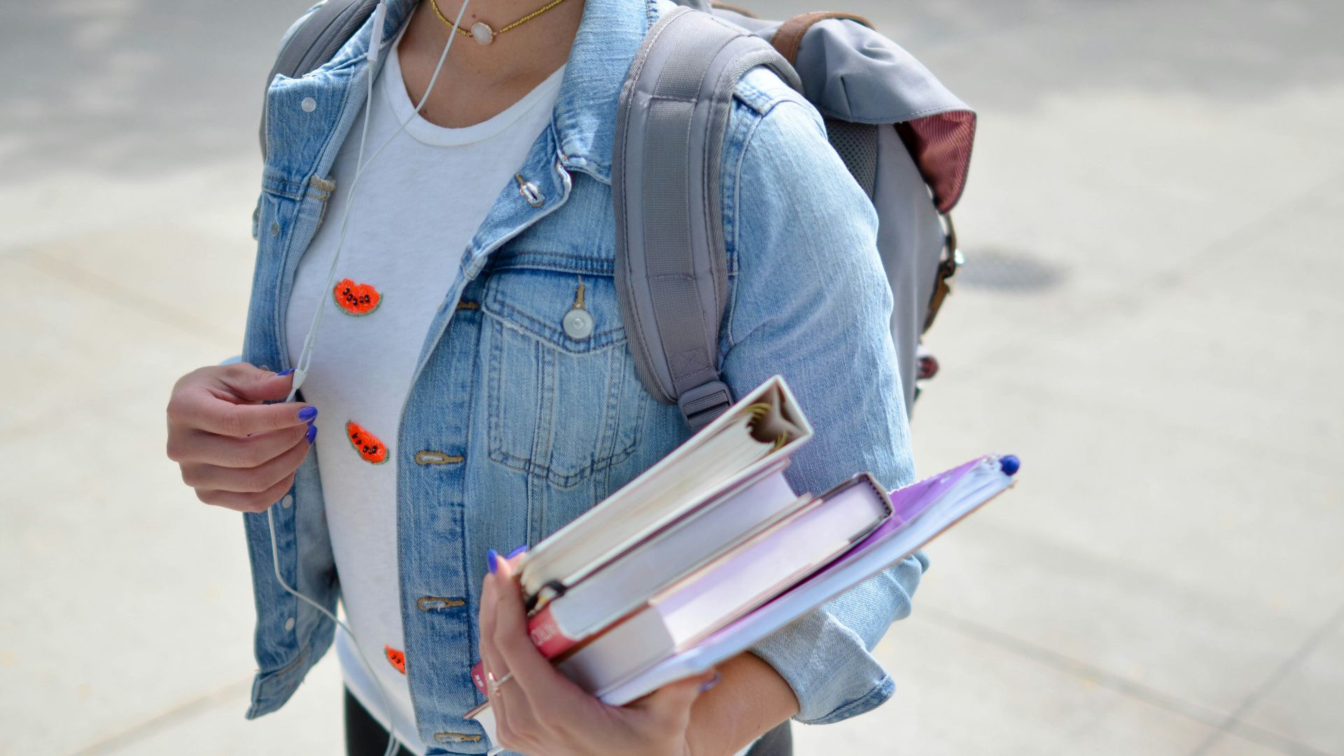 woman wearing blue denim jacket holding book