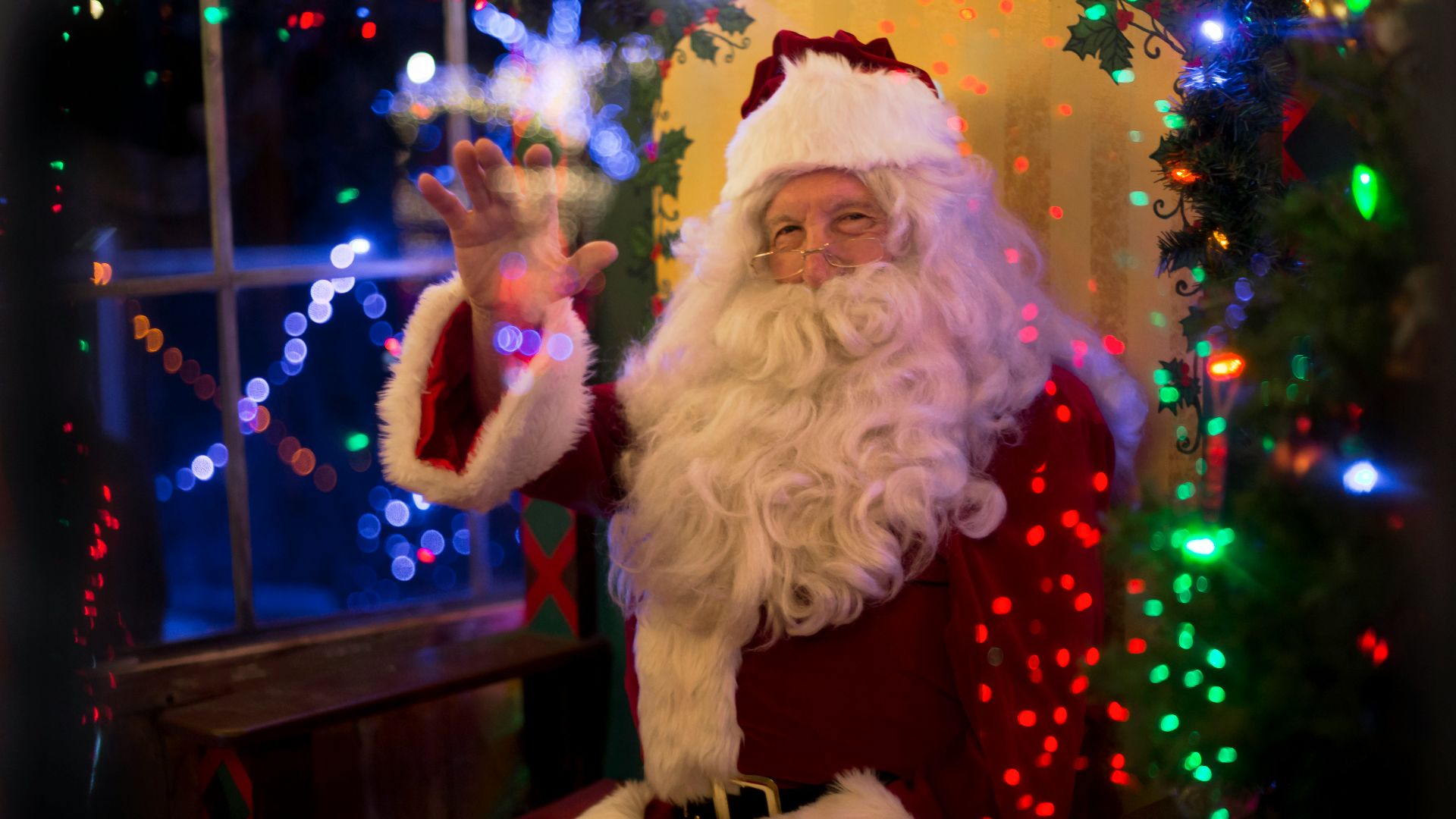 santa claus sitting beside lit tree