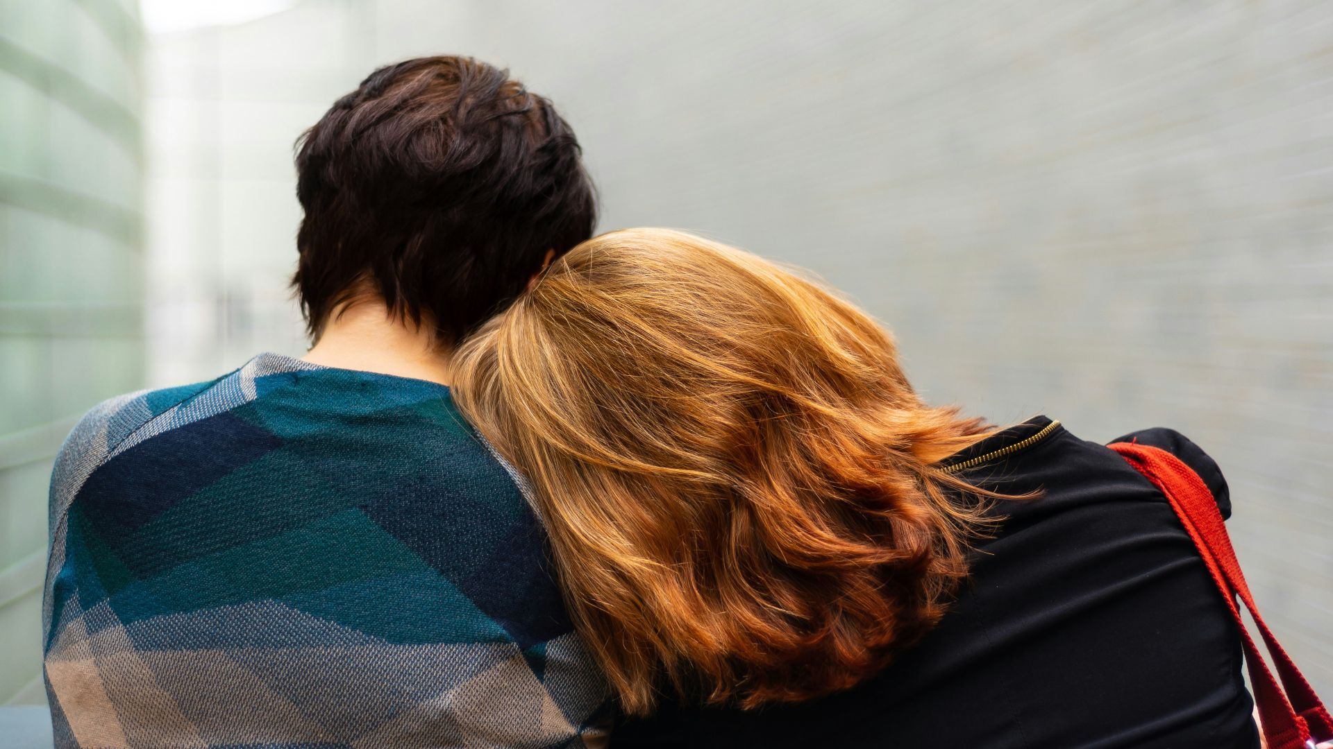a woman rests her head on another person's shoulder