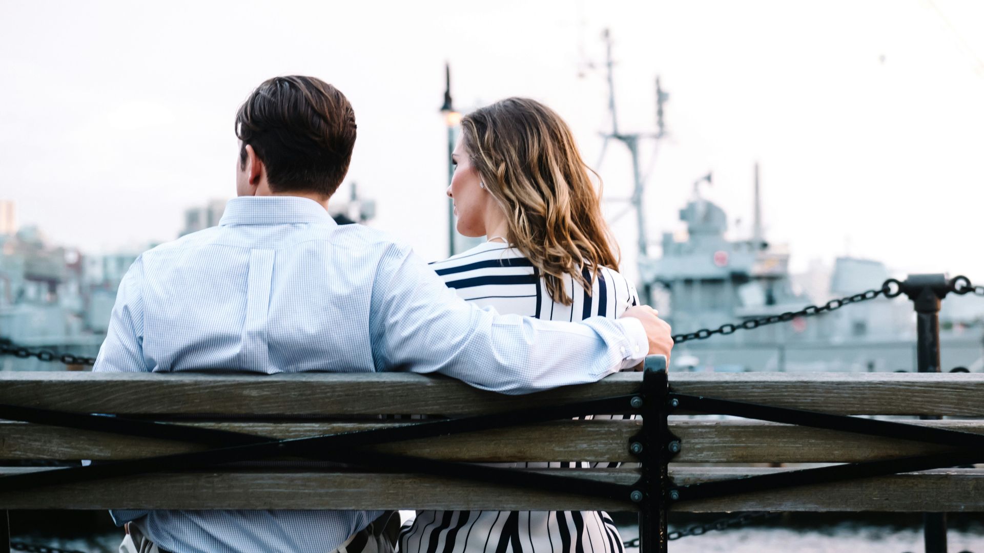 couple sitting on bench near body of water