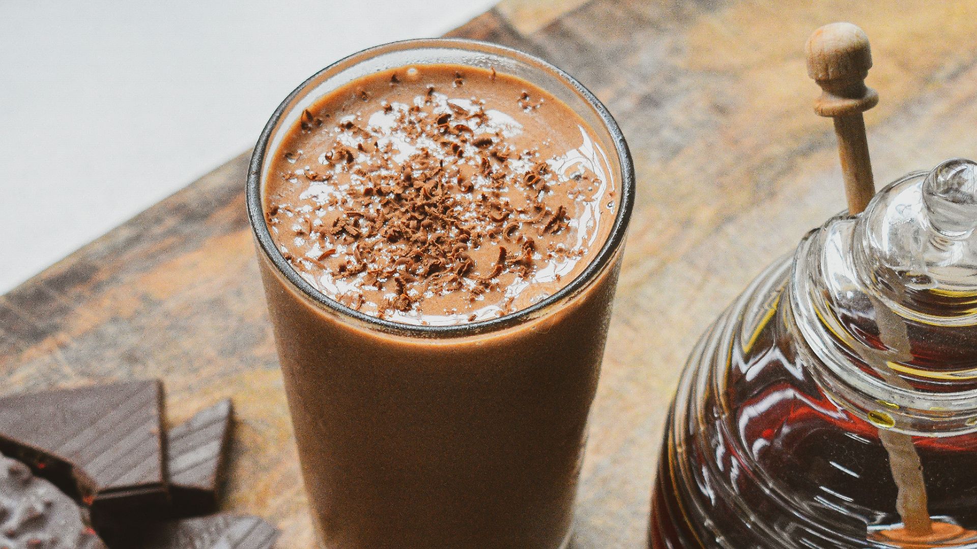 a glass of hot chocolate next to a jar of chocolate
