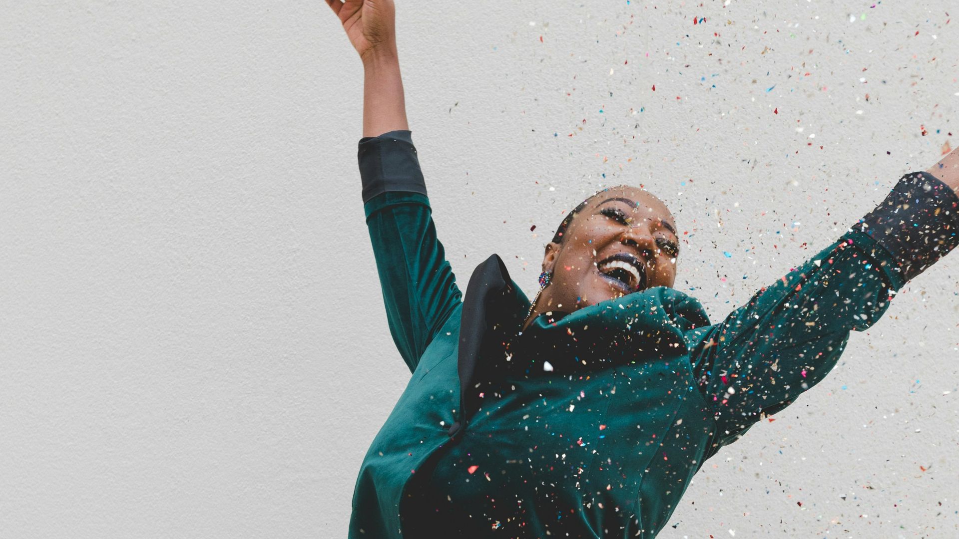 woman in green jacket raising her hands