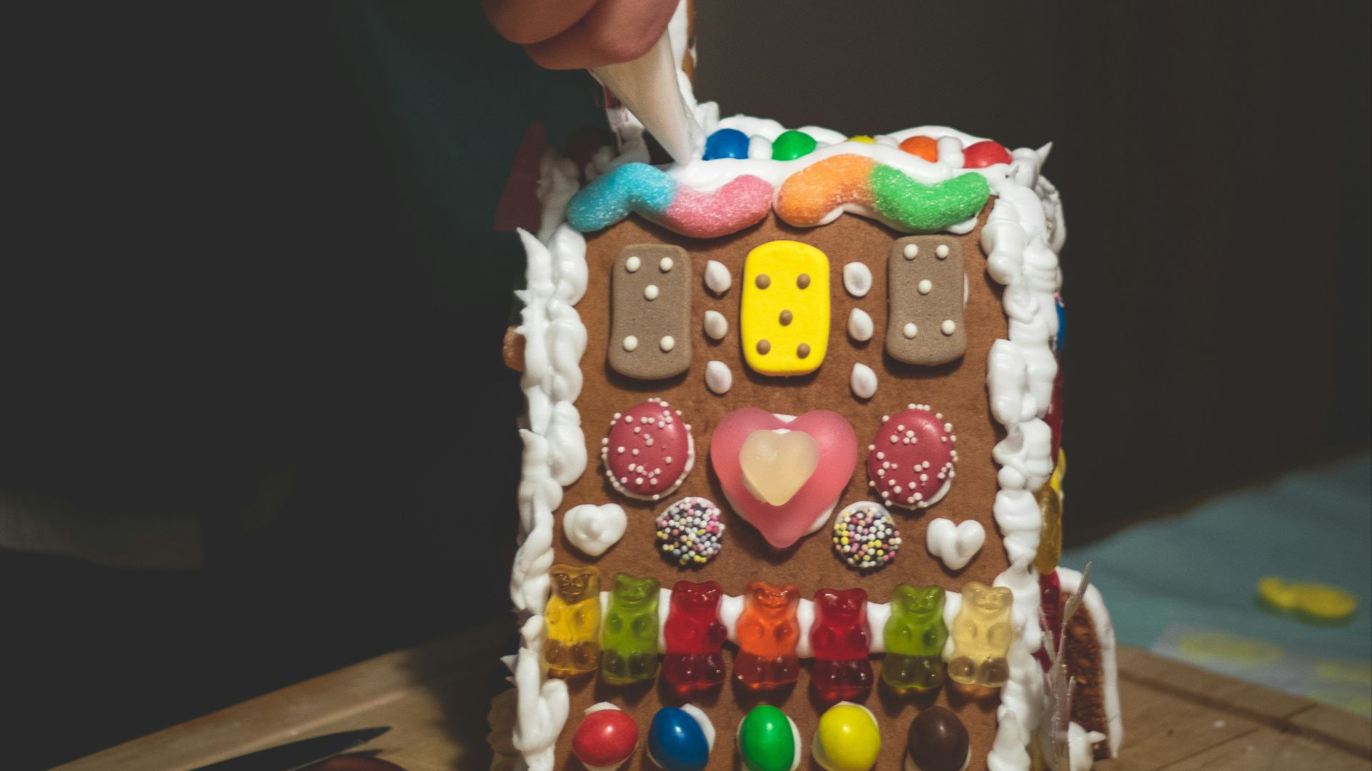 a person decorating a gingerbread house with icing