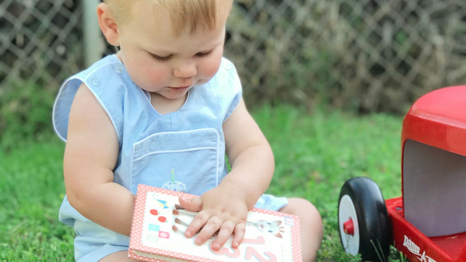 toddler sitting on grass during day