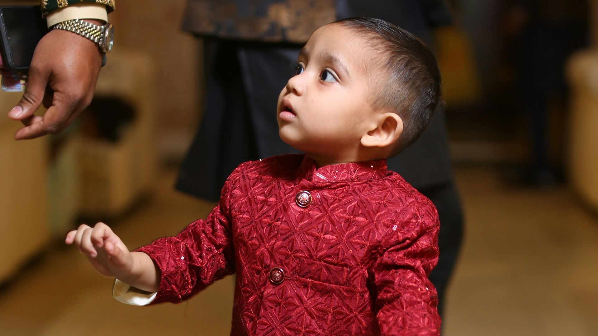 A little boy in a red jacket and white pants
