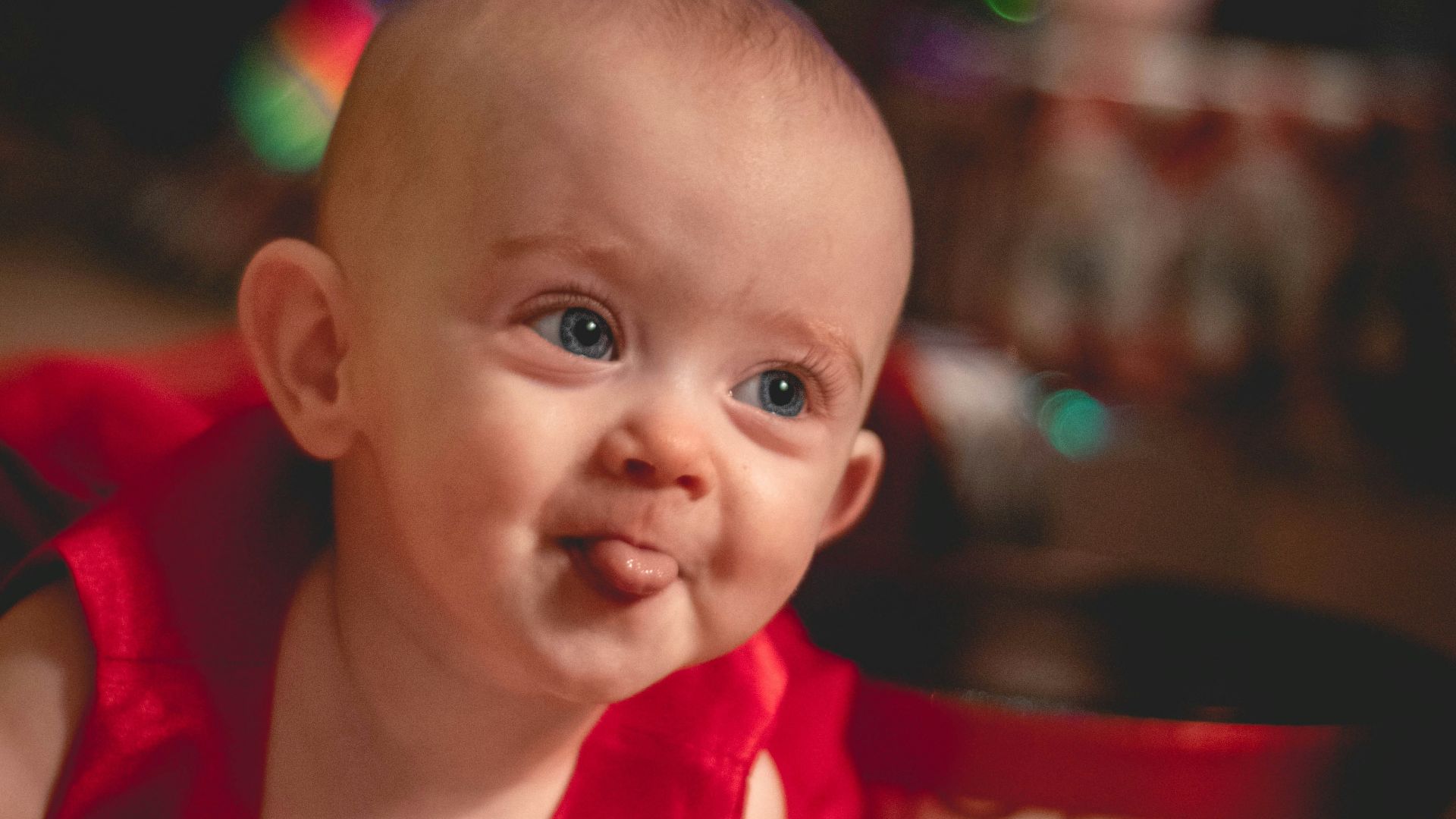 child sticking tongue out by Christmas tree