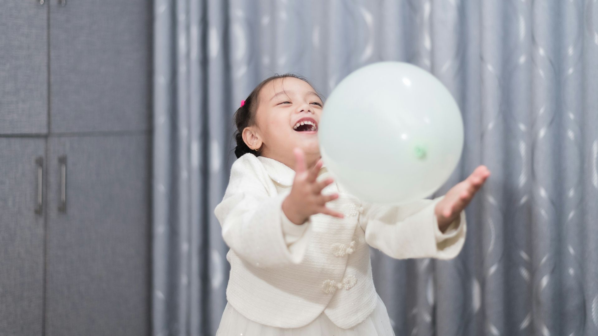 a little girl holding a white balloon in her hand