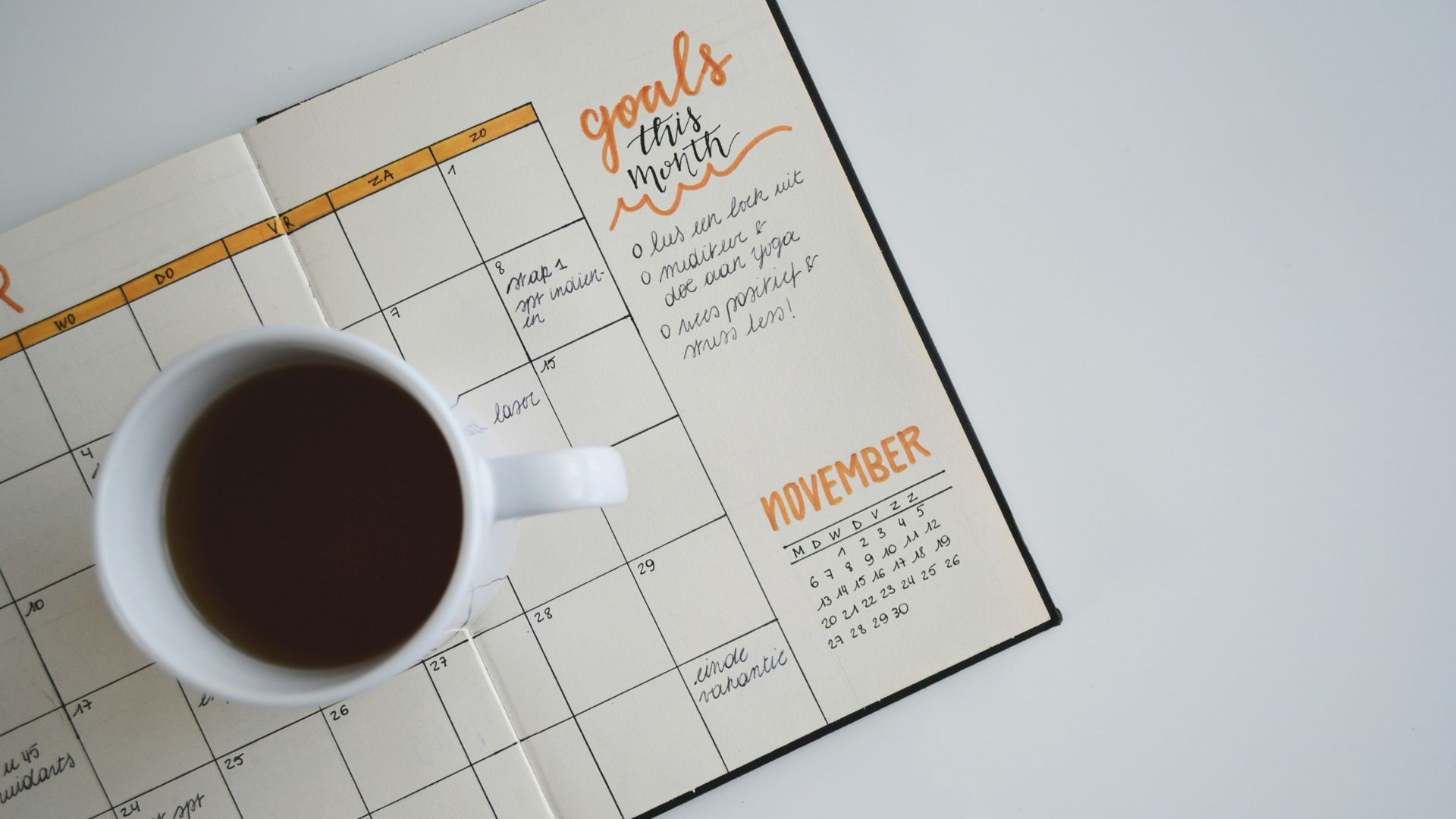white ceramic mug with coffee on top of a planner
