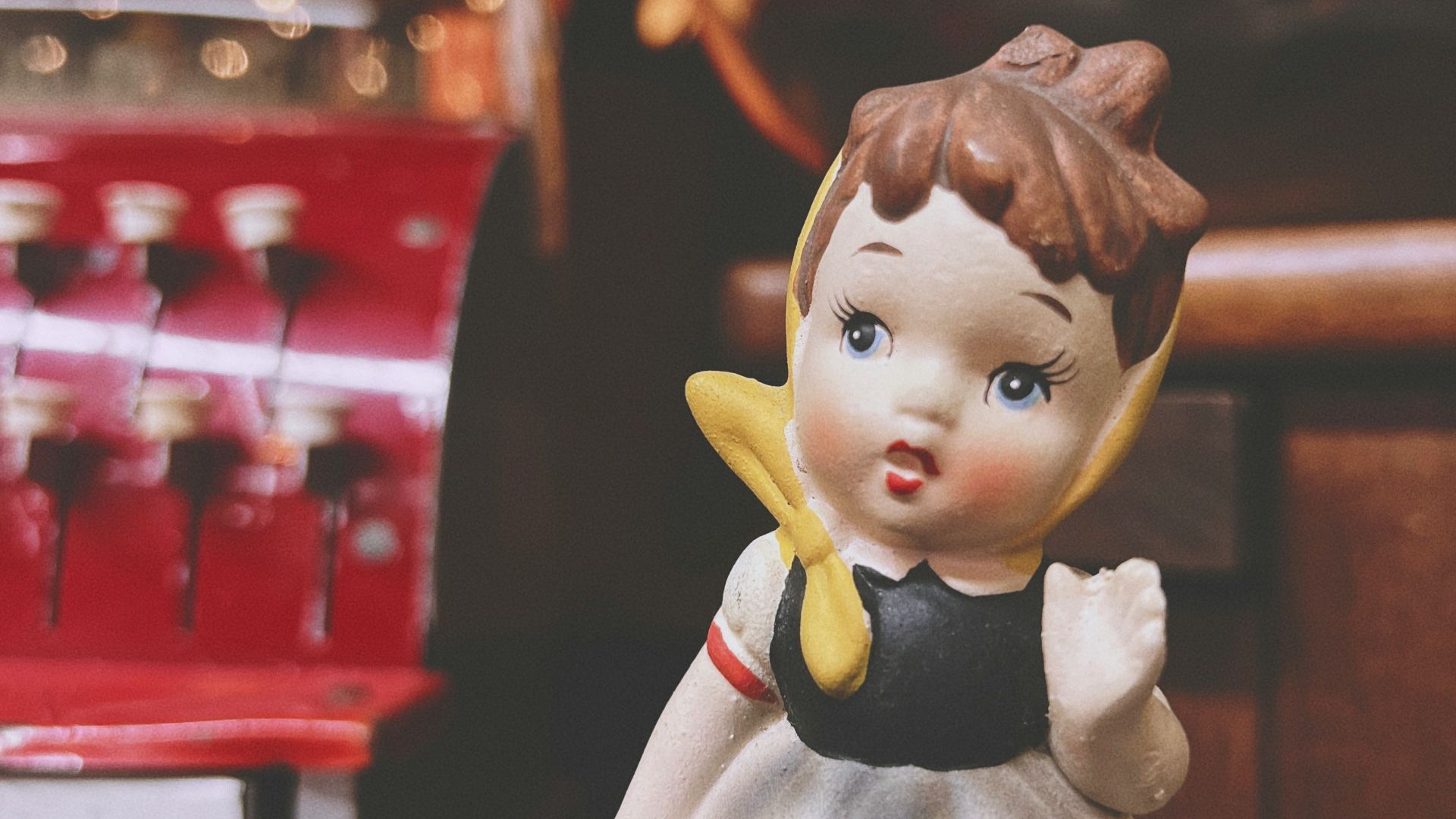 A little girl figurine next to a coca cola machine