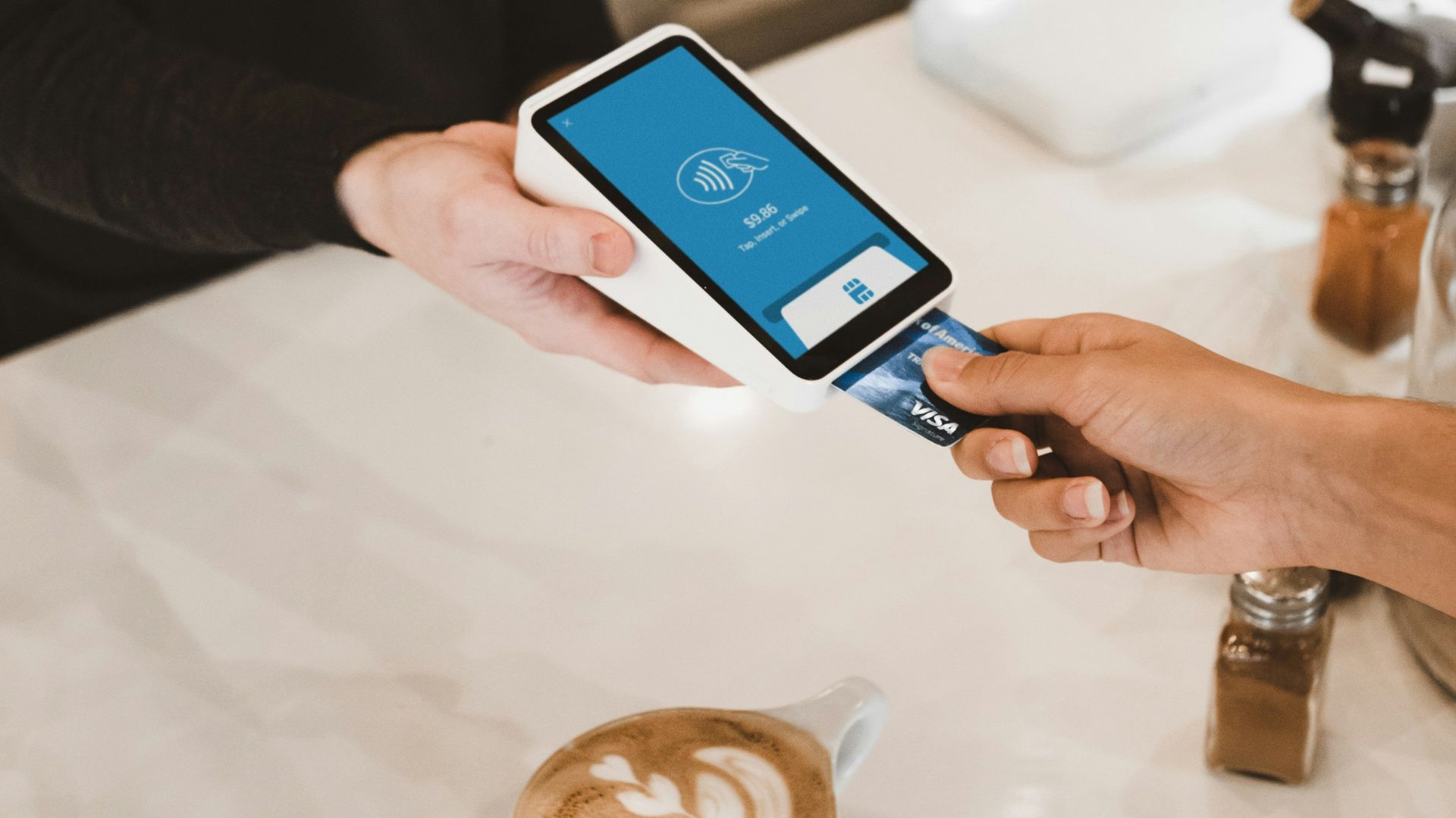 person putting magstripe card near black card terminal