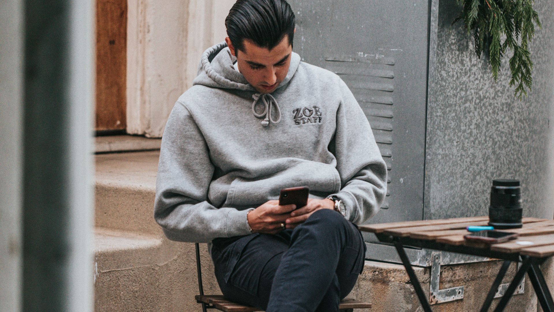 man in gray sweater sitting on brown wooden folding table