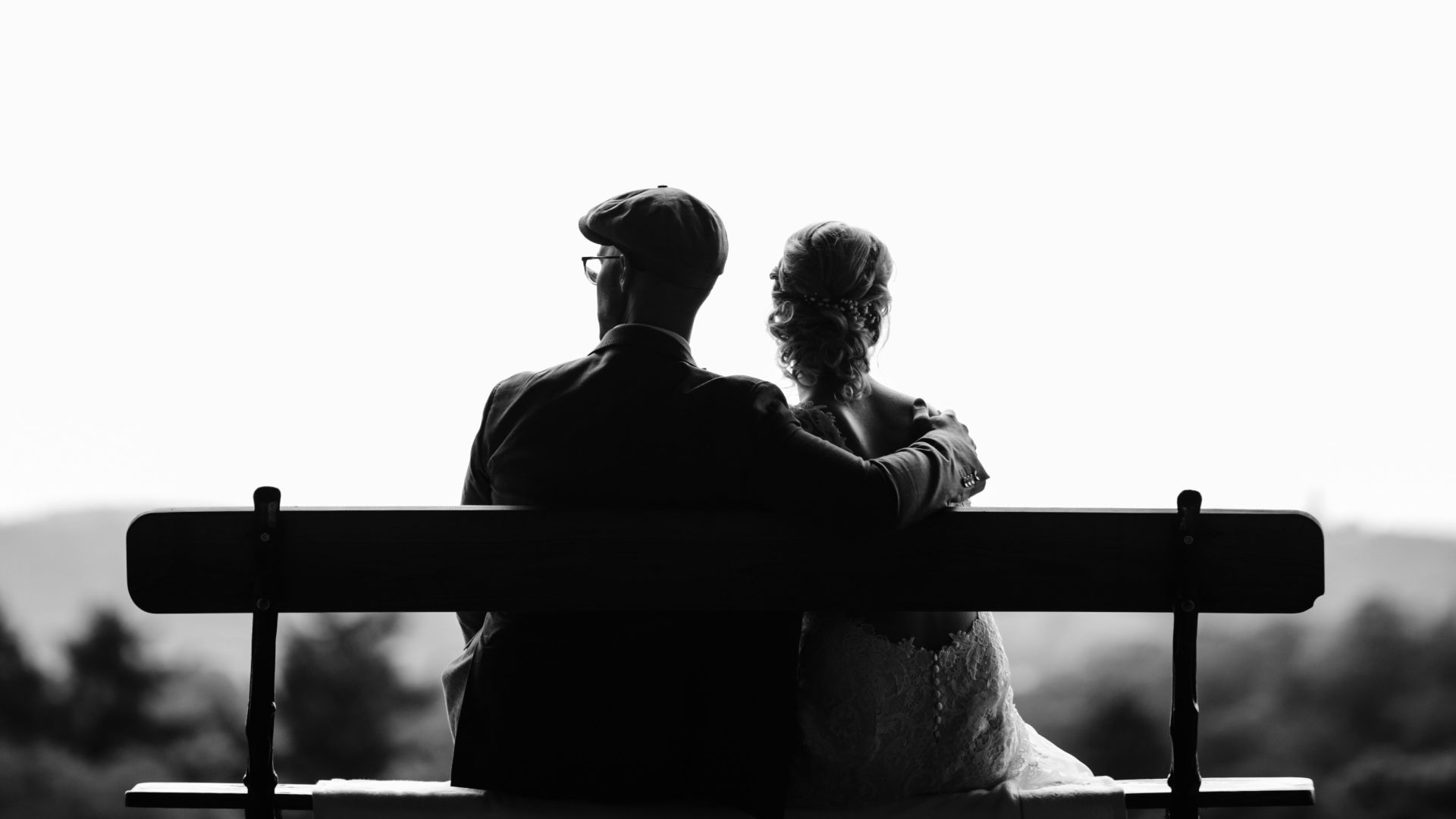 couple sitting on bench under tree grayscale photography