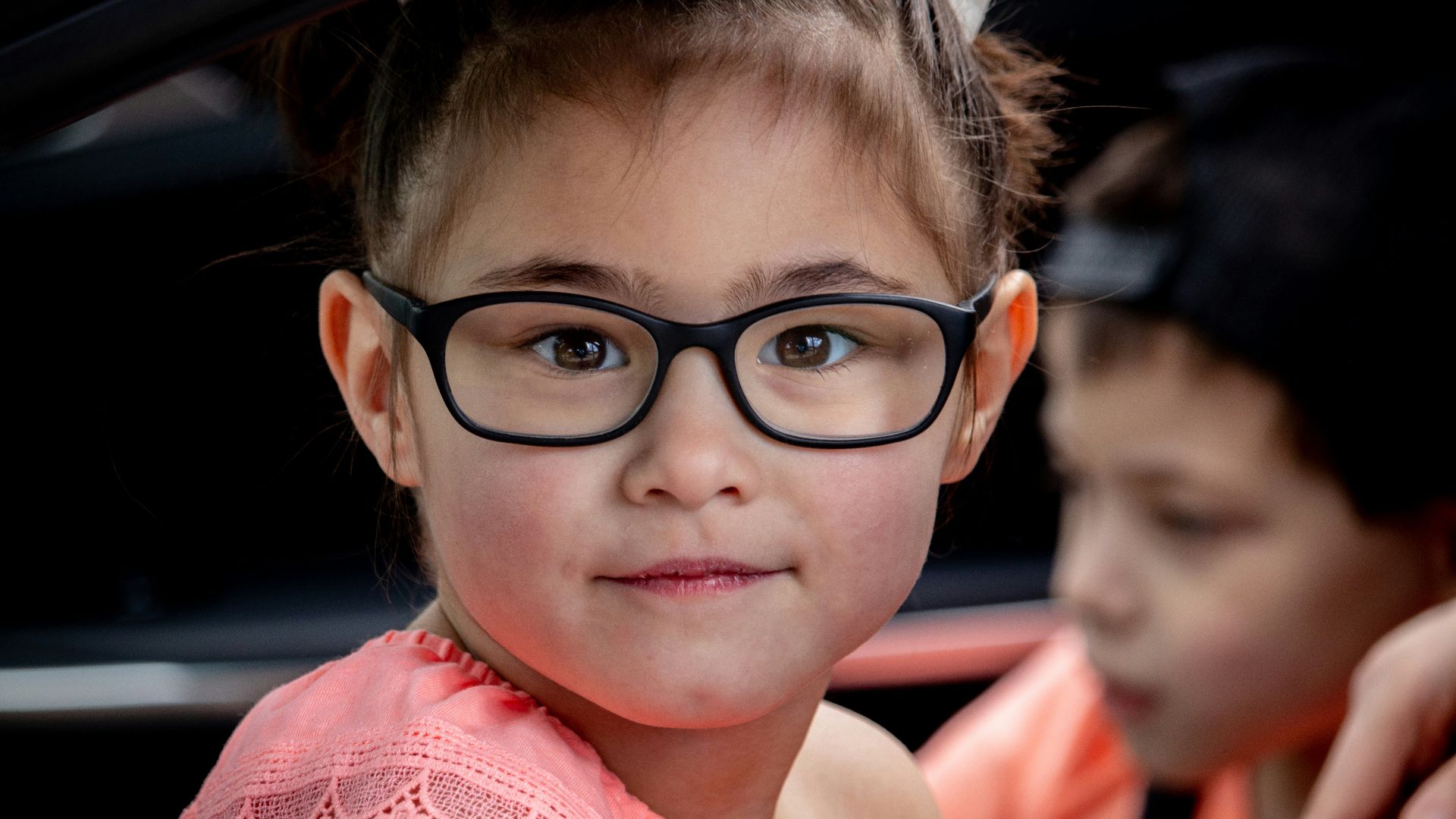 girl in pink sleeveless shirt wearing black framed eyeglasses