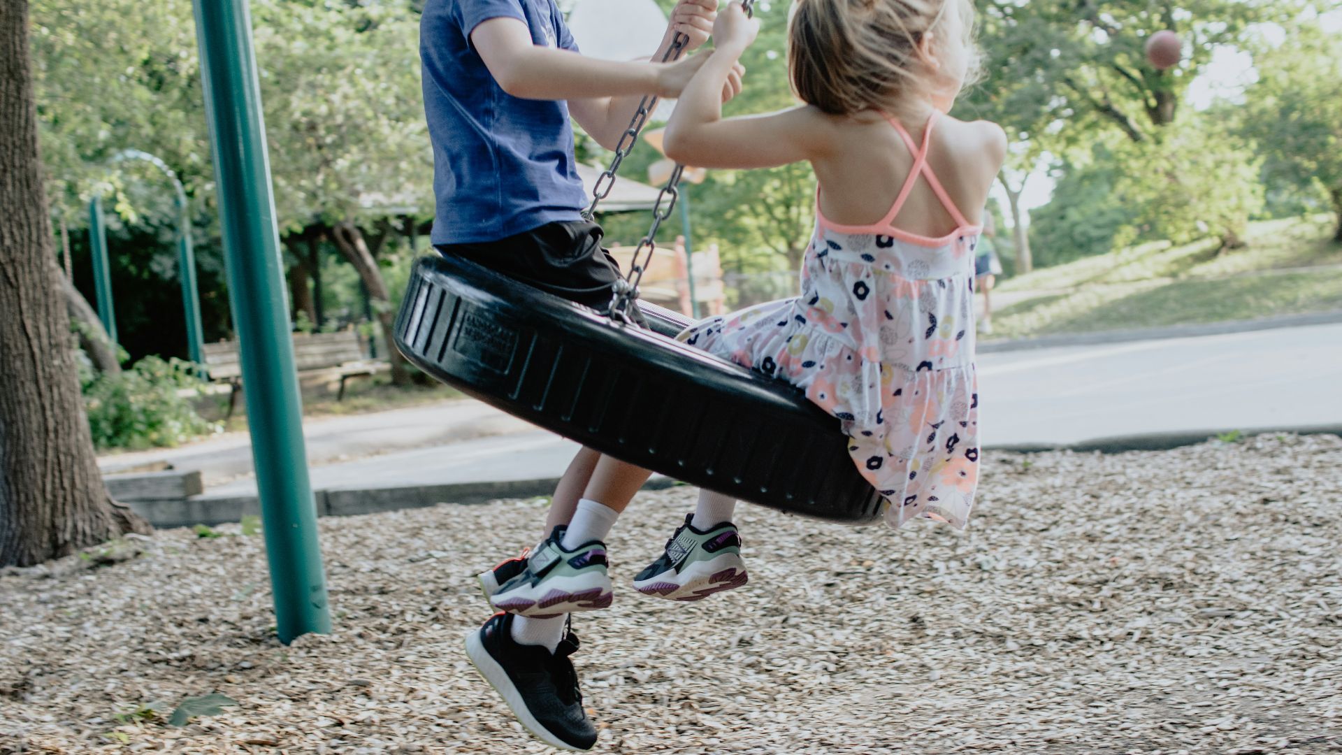 girl in pink and white floral dress riding on swing during daytime