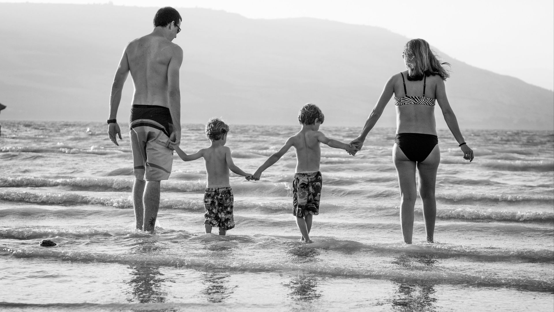 grayscale photography of family walking on beach
