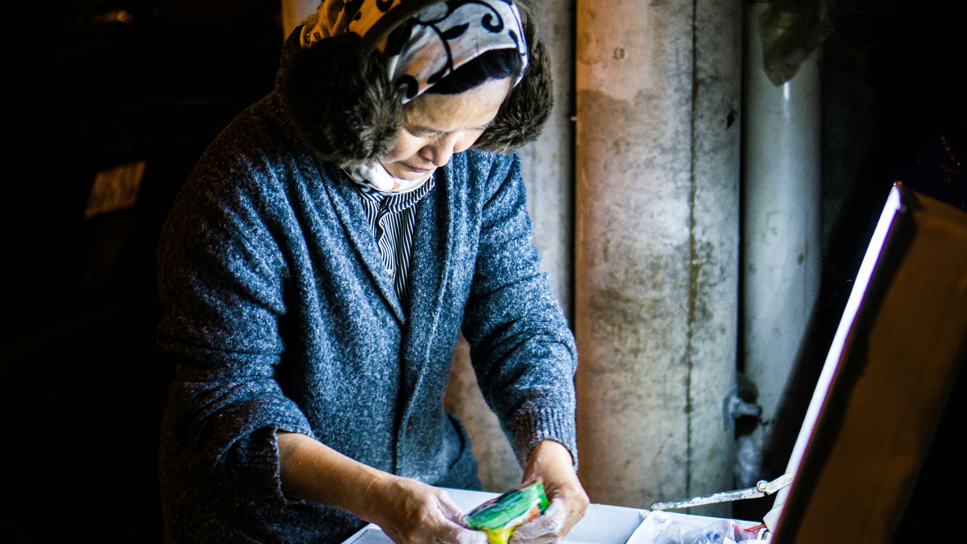 woman wearing blue knit jacket holding green labeled pack