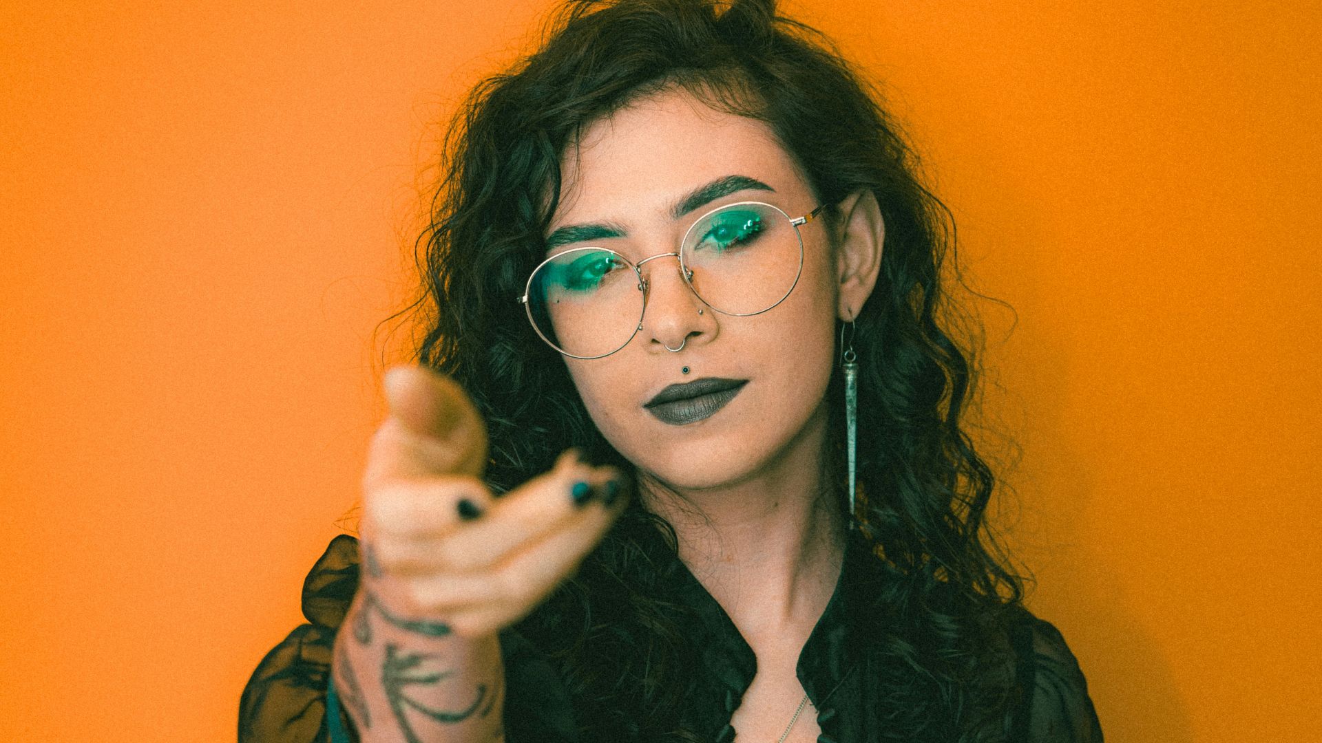 a woman with green glasses pointing at the camera