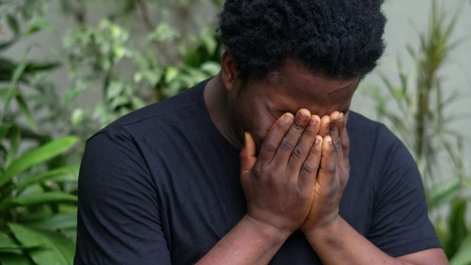 a man covers his face with his hands