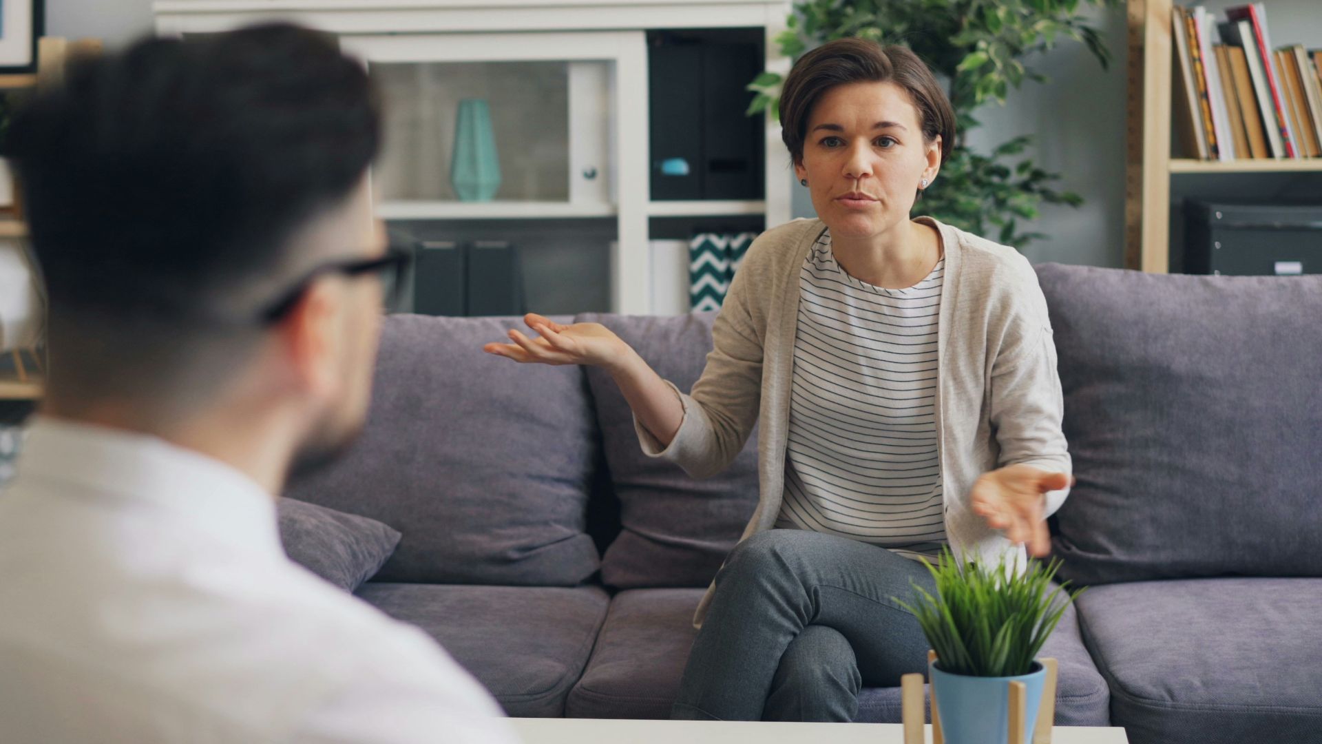 a woman sitting on a couch talking to a man