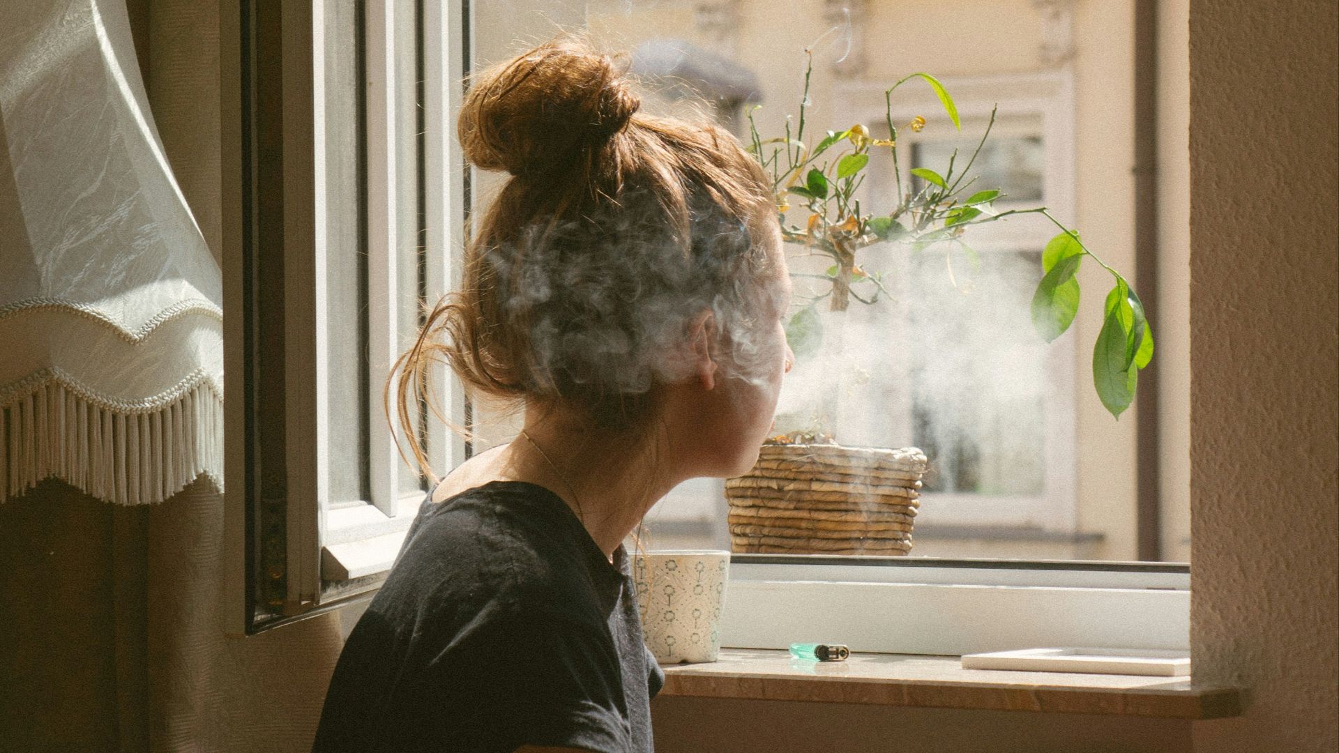 woman smoking while look through the window