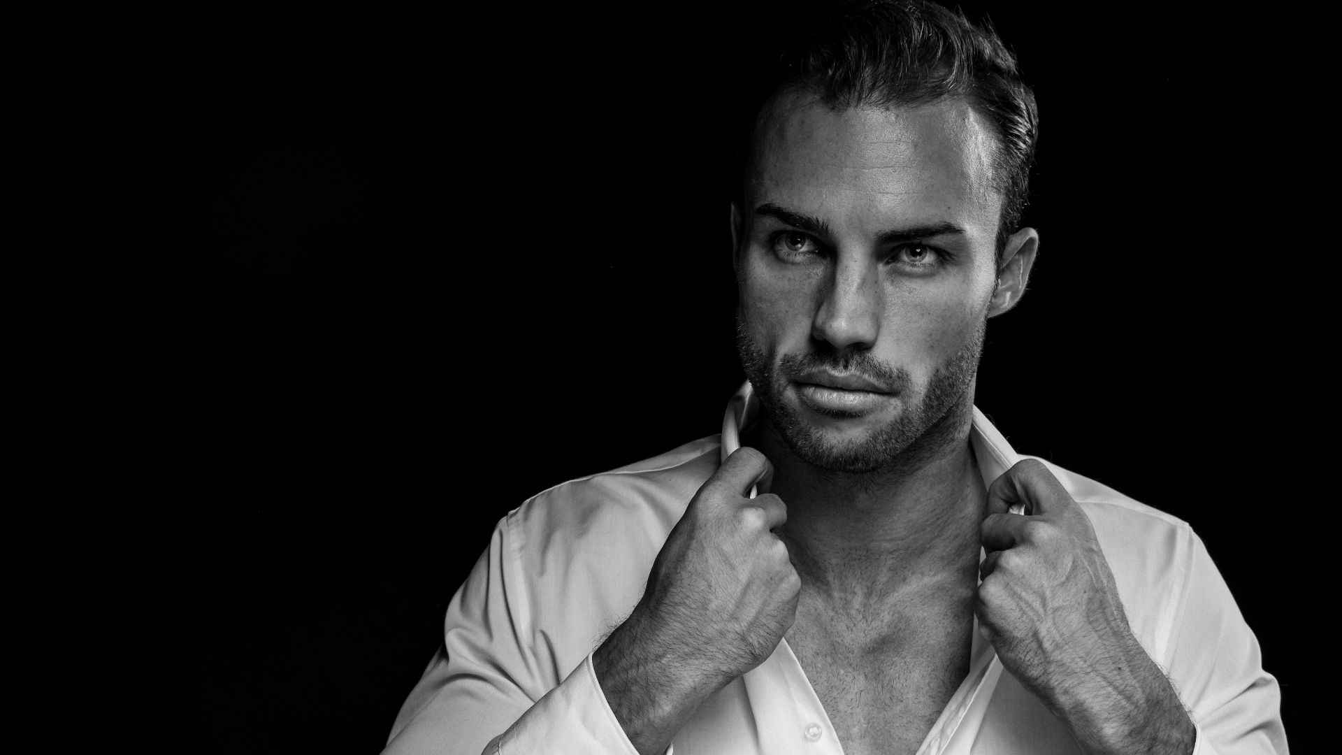 grayscale portrait of man wearing white dress shirt on black background