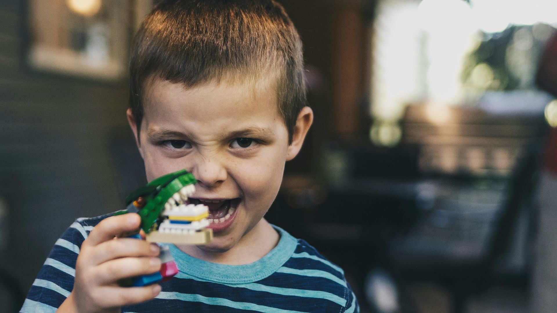 boy wearing teal and black striped t-shirt holding toy