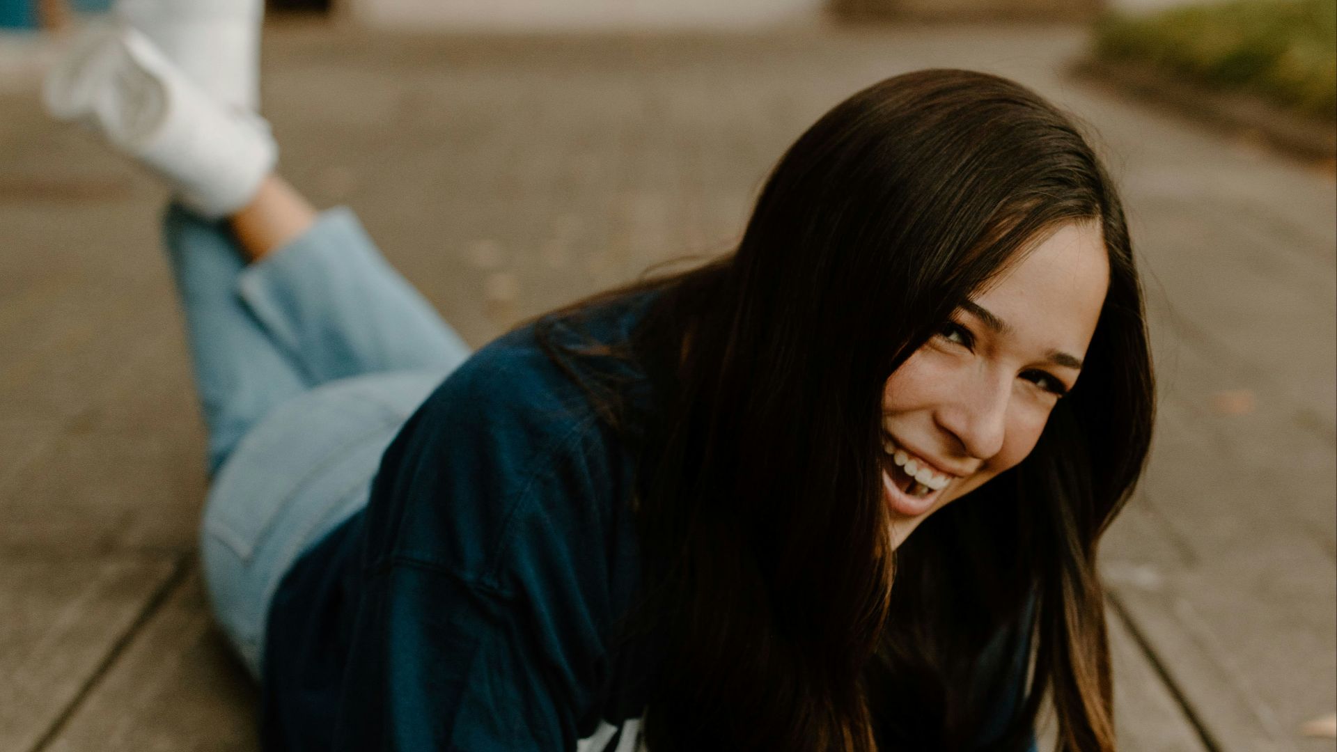 woman in blue t-shirt and blue denim jeans sitting on concrete floor during daytime