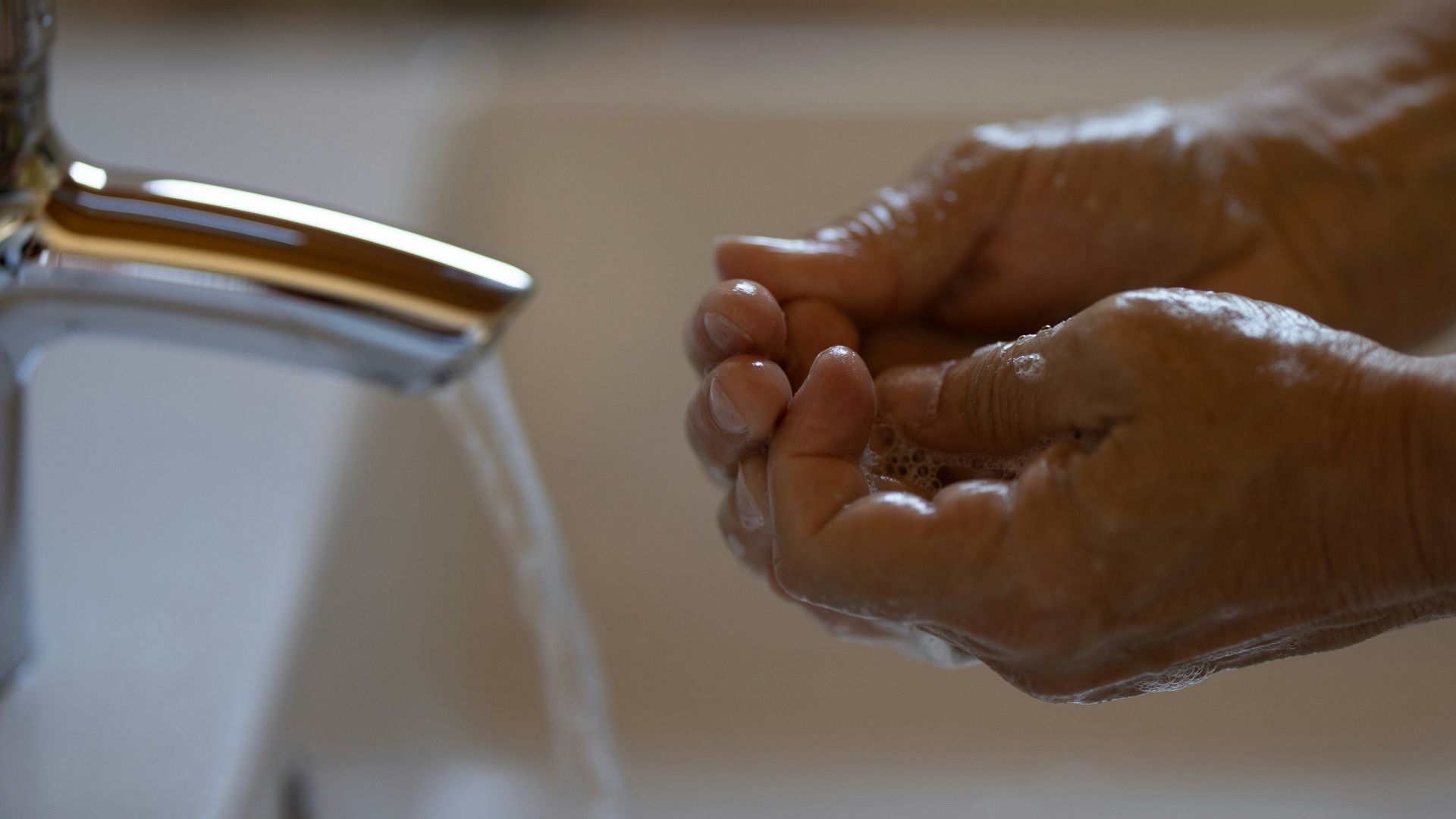 person washing hands on faucet