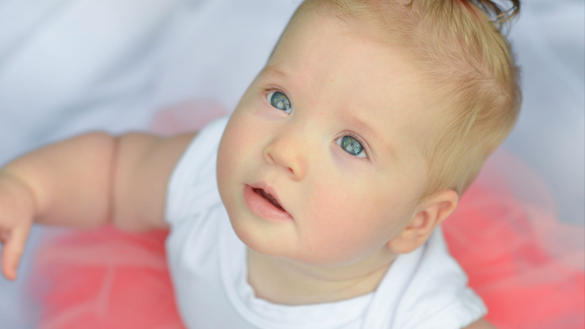 baby in white shirt lying on bed