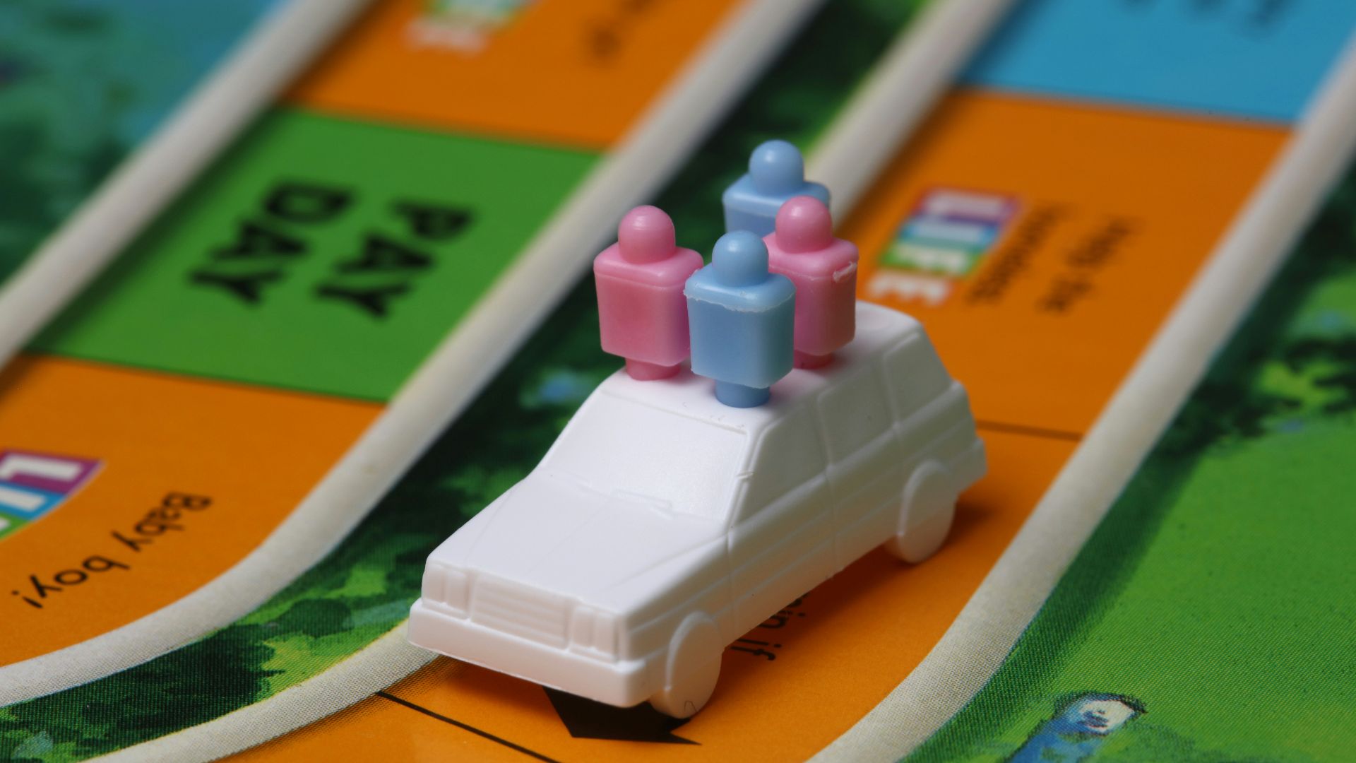 white and blue car toy on top of orange game board