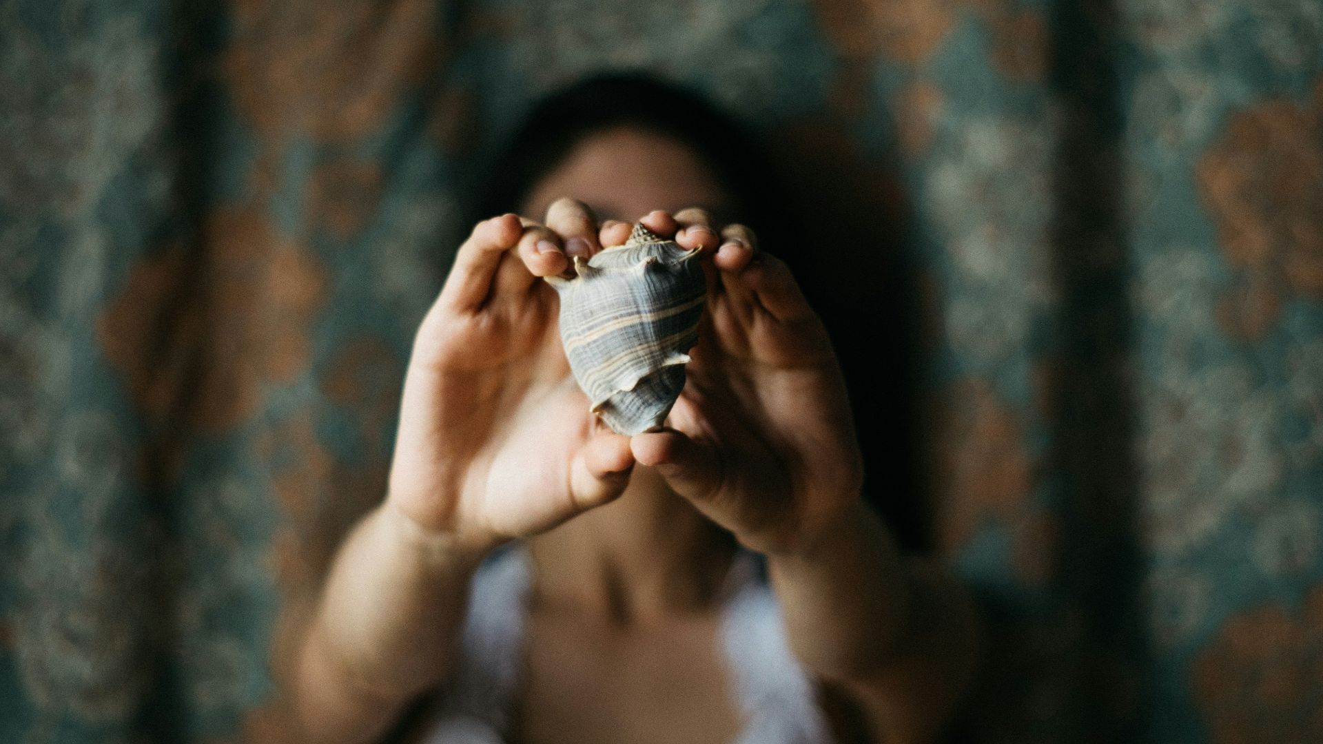 selective focus photography of woman showing conch shell