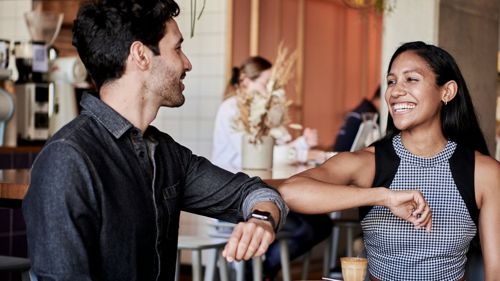 man in black shirt elbow bumping with woman in a restaurant