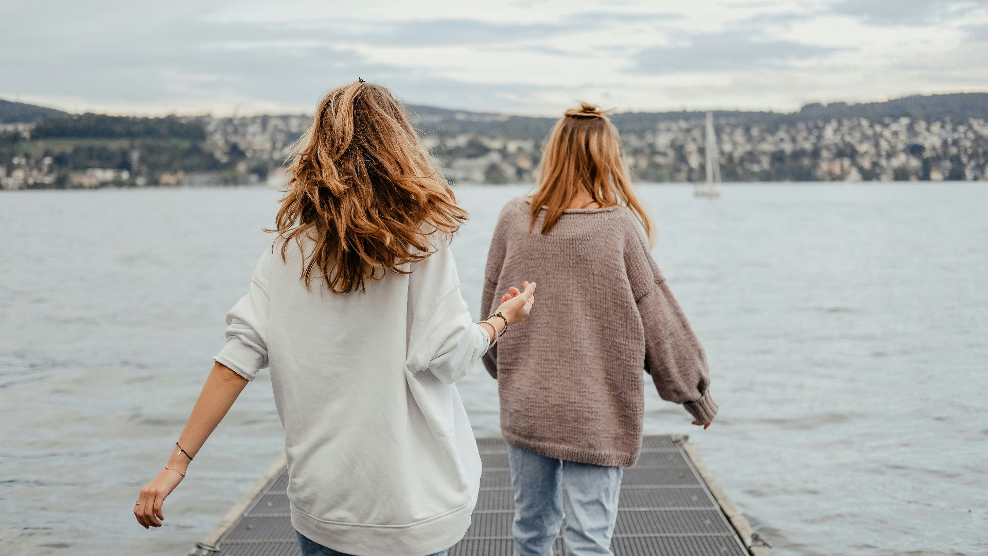 two women standing on dock front of sea at daytime