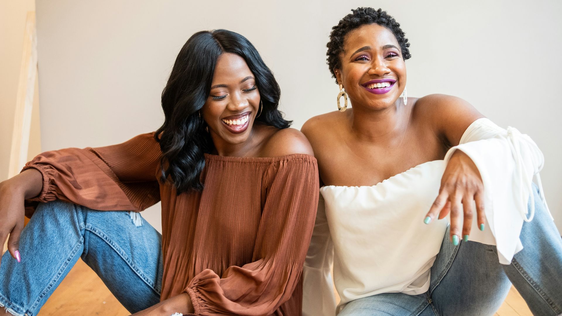 woman in white tube dress sitting beside woman in brown dress
