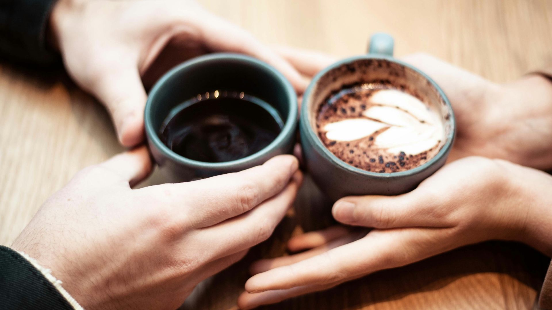 two person holding ceramic mugs with coffee
