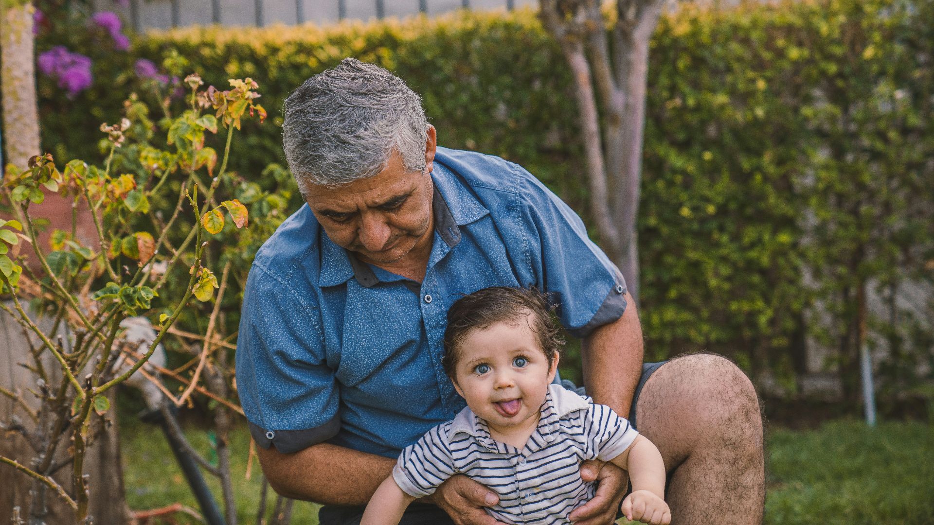 man in blue button up shirt carrying baby in black and white stripe shirt