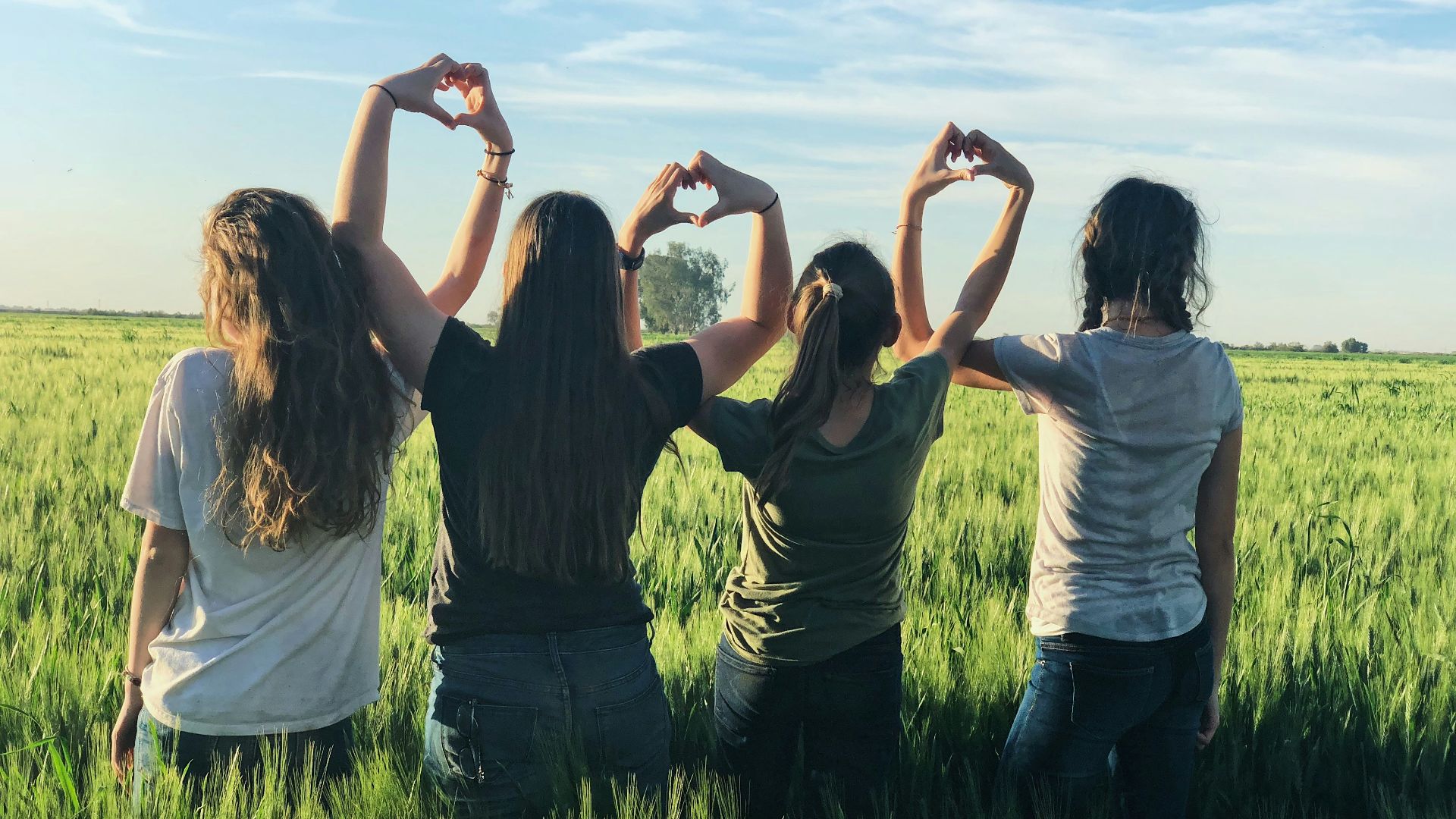 women forming heart gestures during daytime