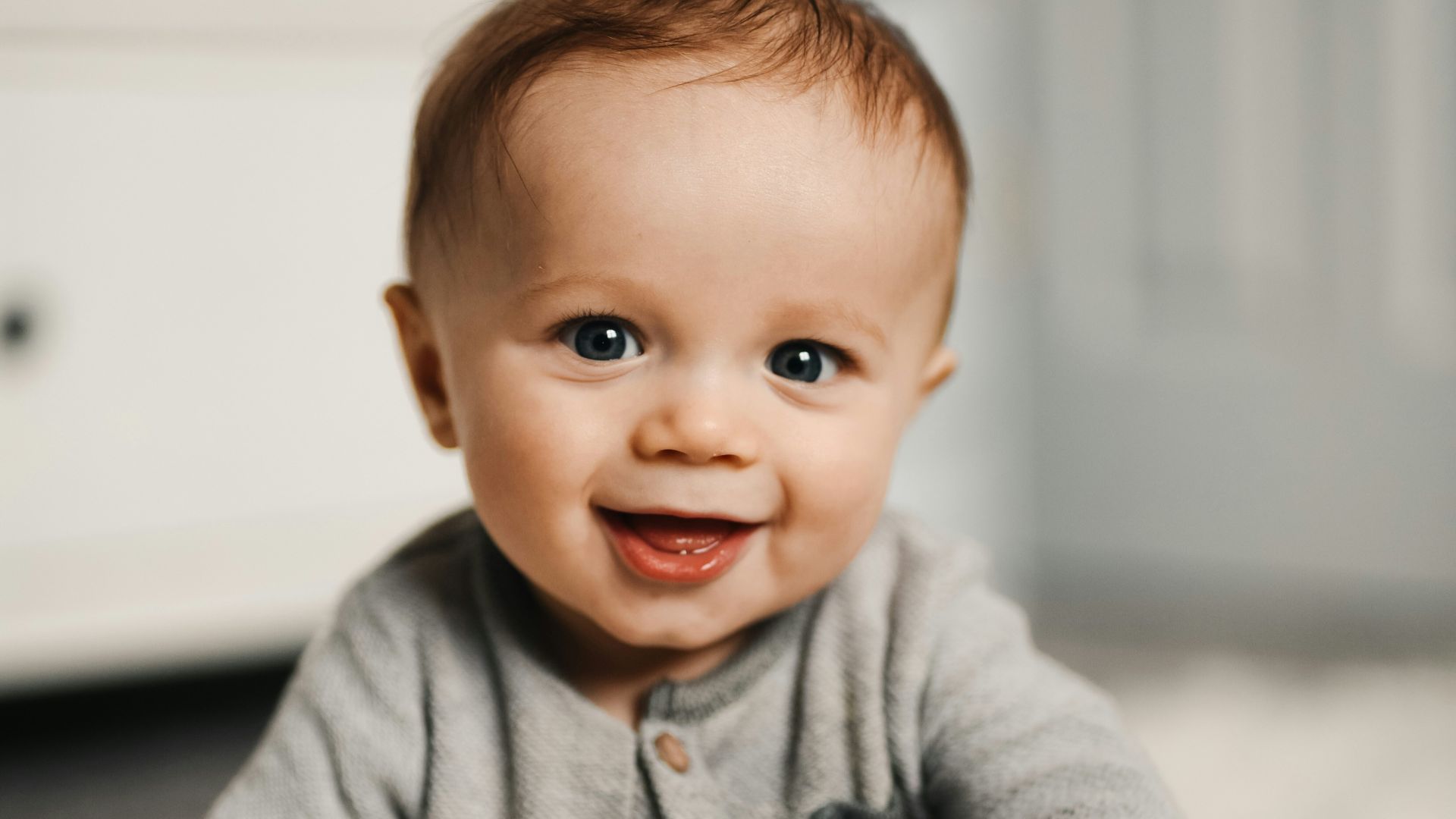 baby in gray sweater lying on white textile