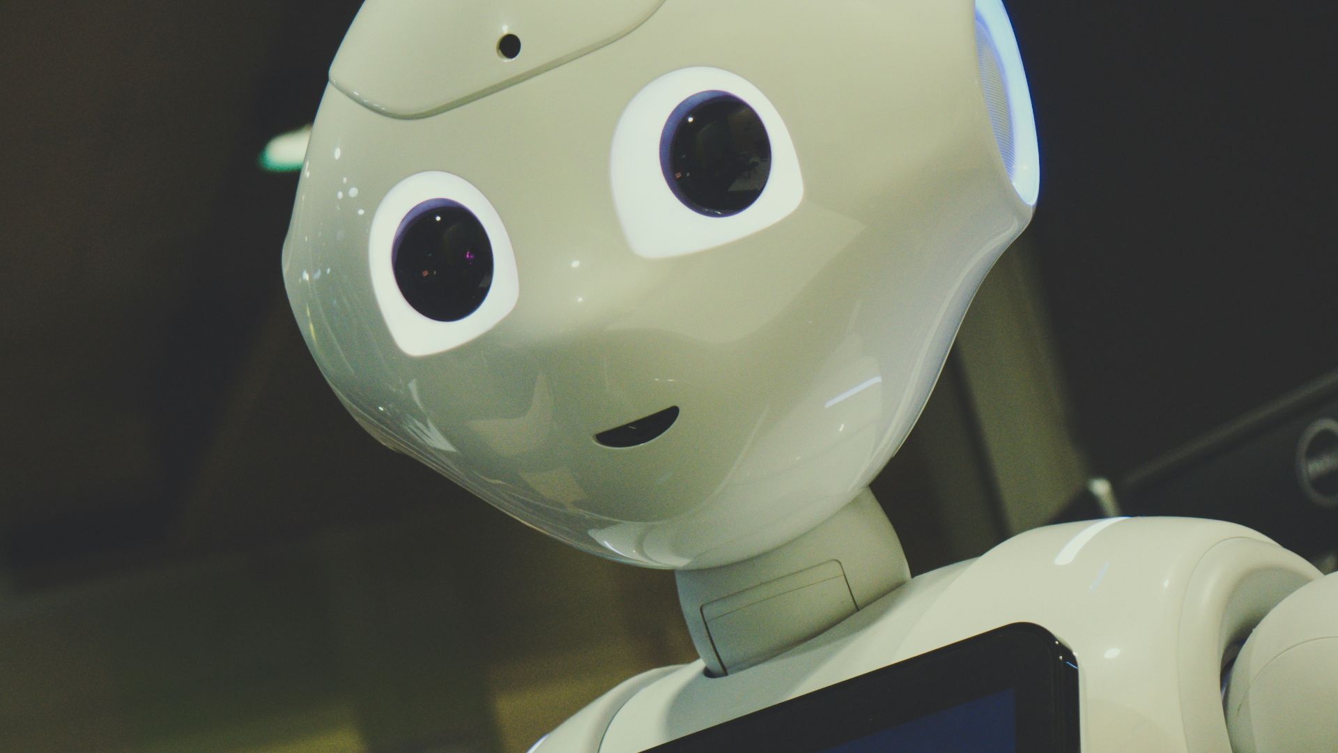 white robot toy holding black tablet