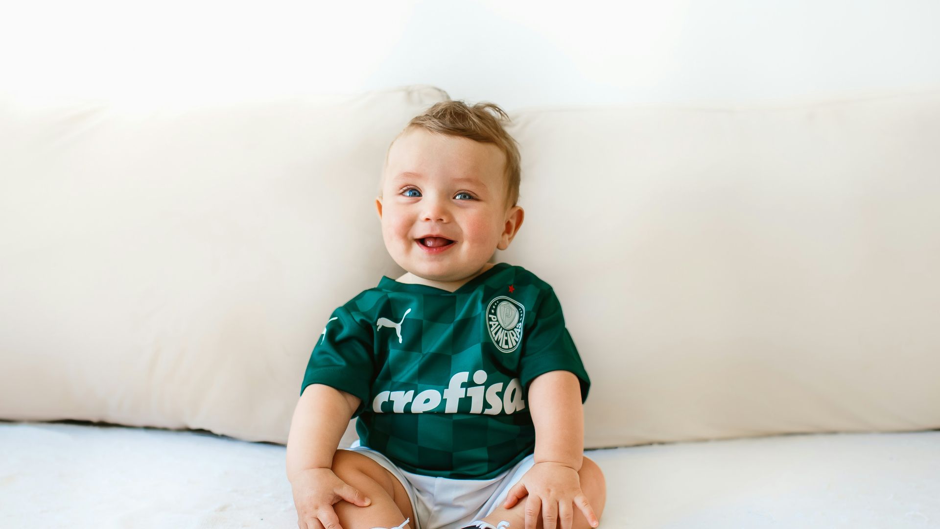 boy in green and white crew neck t-shirt sitting on white bed