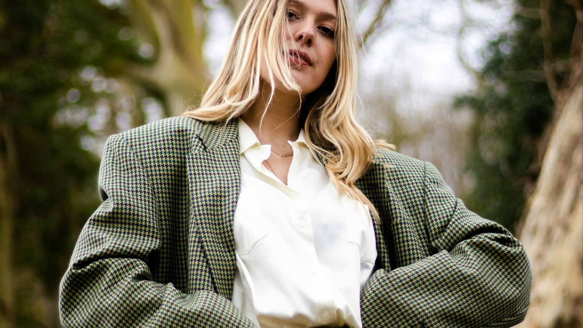 woman in gray and white polka dot blazer standing and smiling