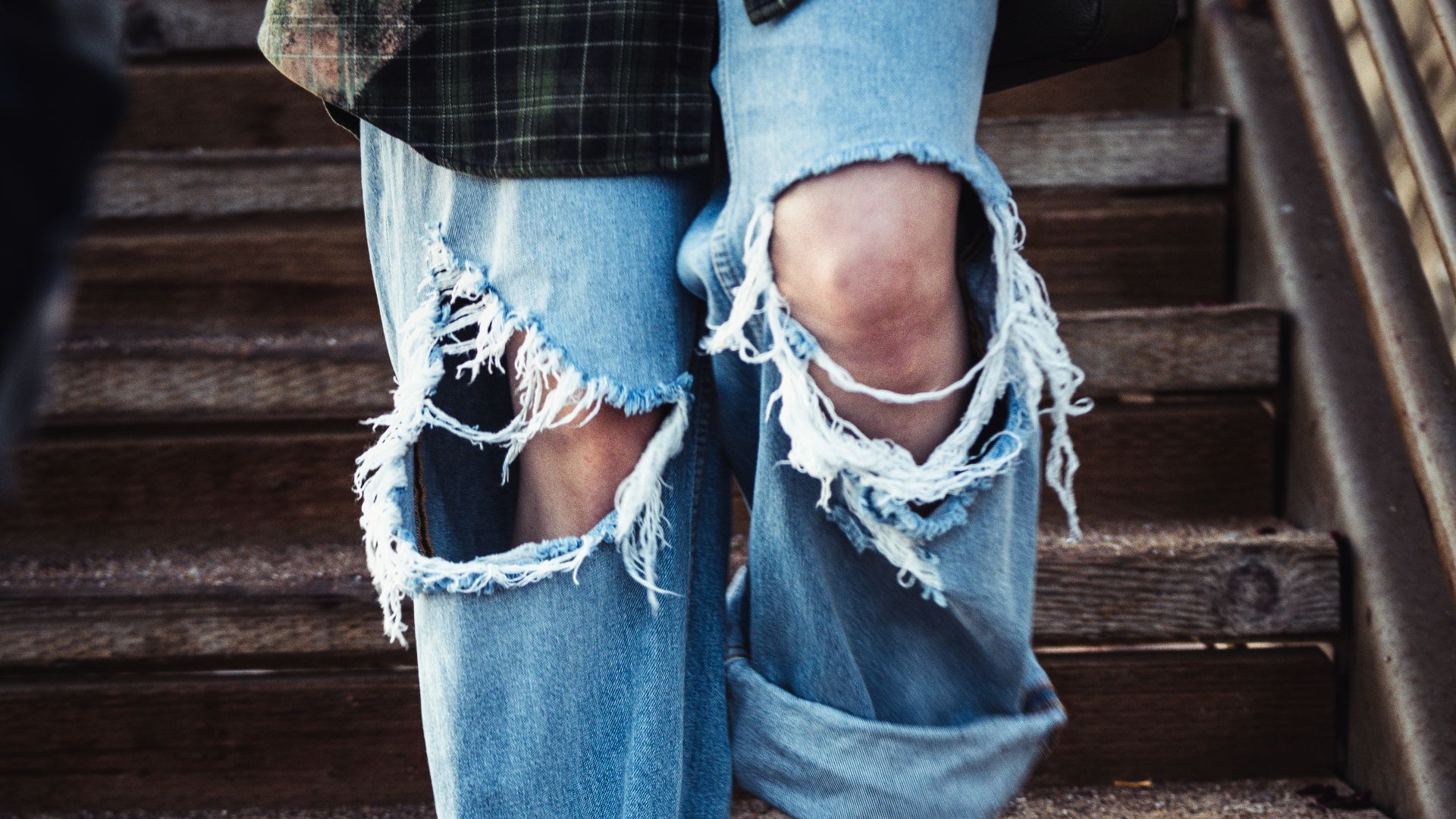 a person's legs in jeans and a blue shirt on a wooden staircase