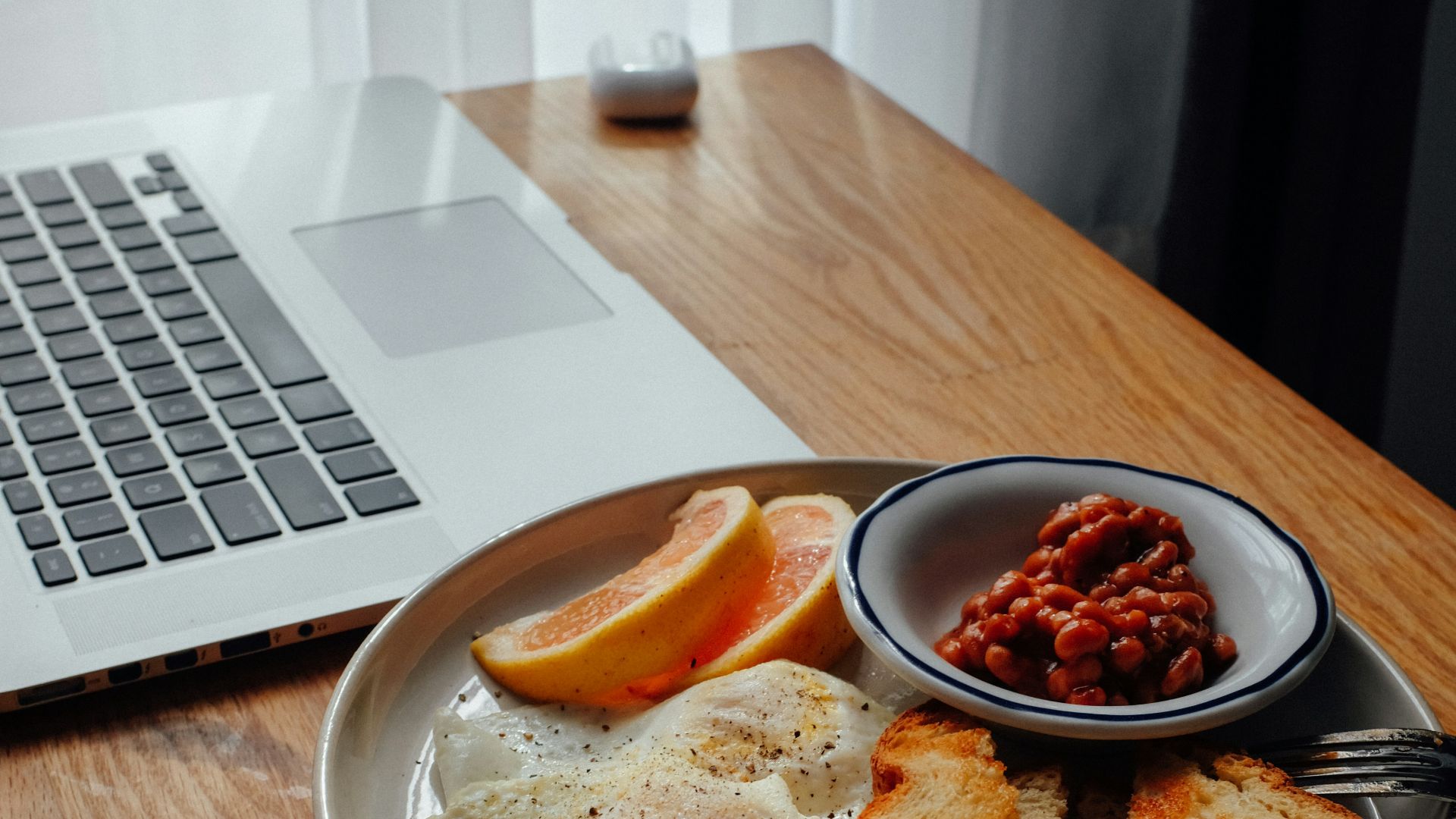burger on brown wooden round plate beside black ceramic mug