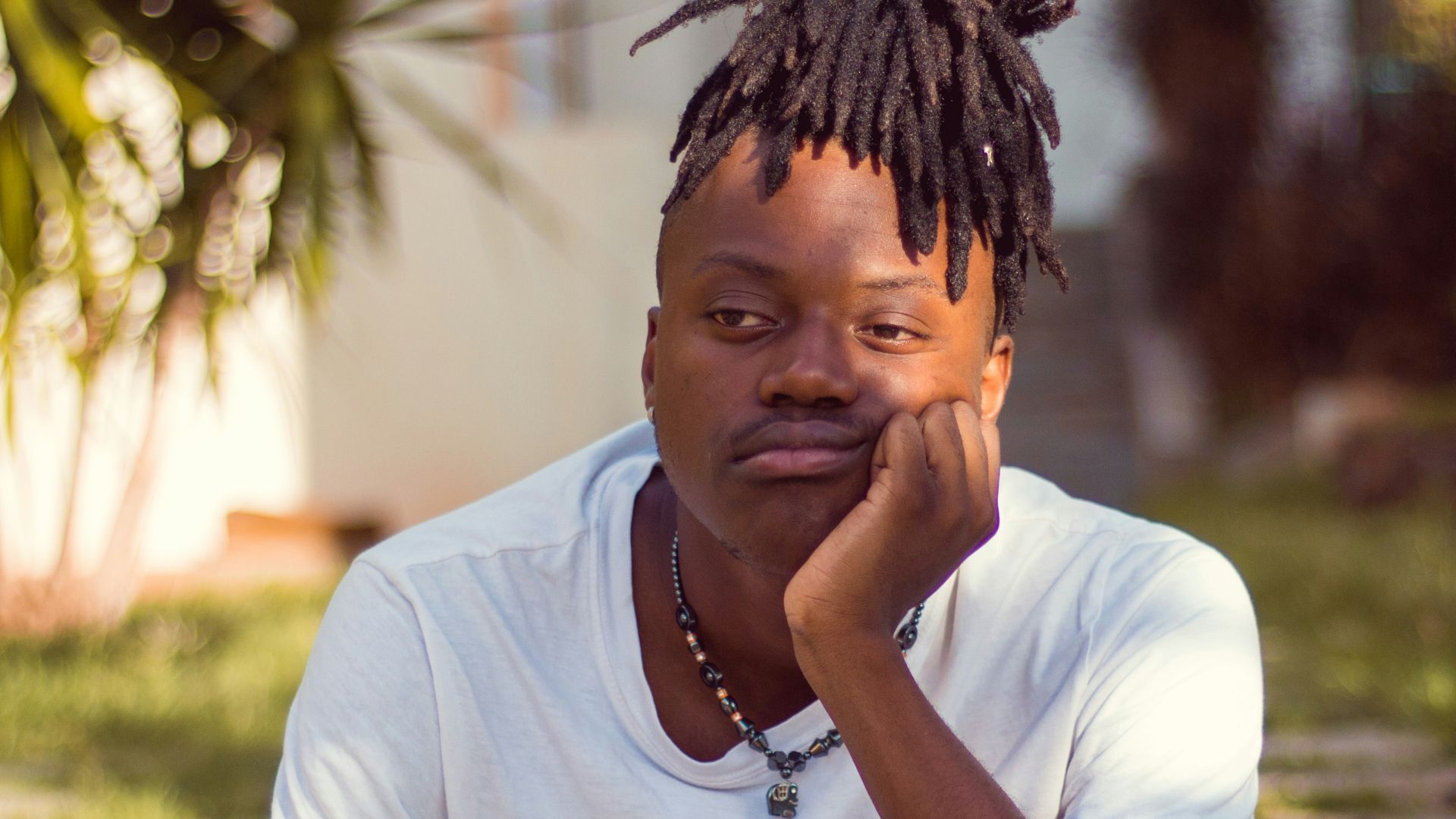 man in white crew neck t-shirt sitting on brown wooden chair